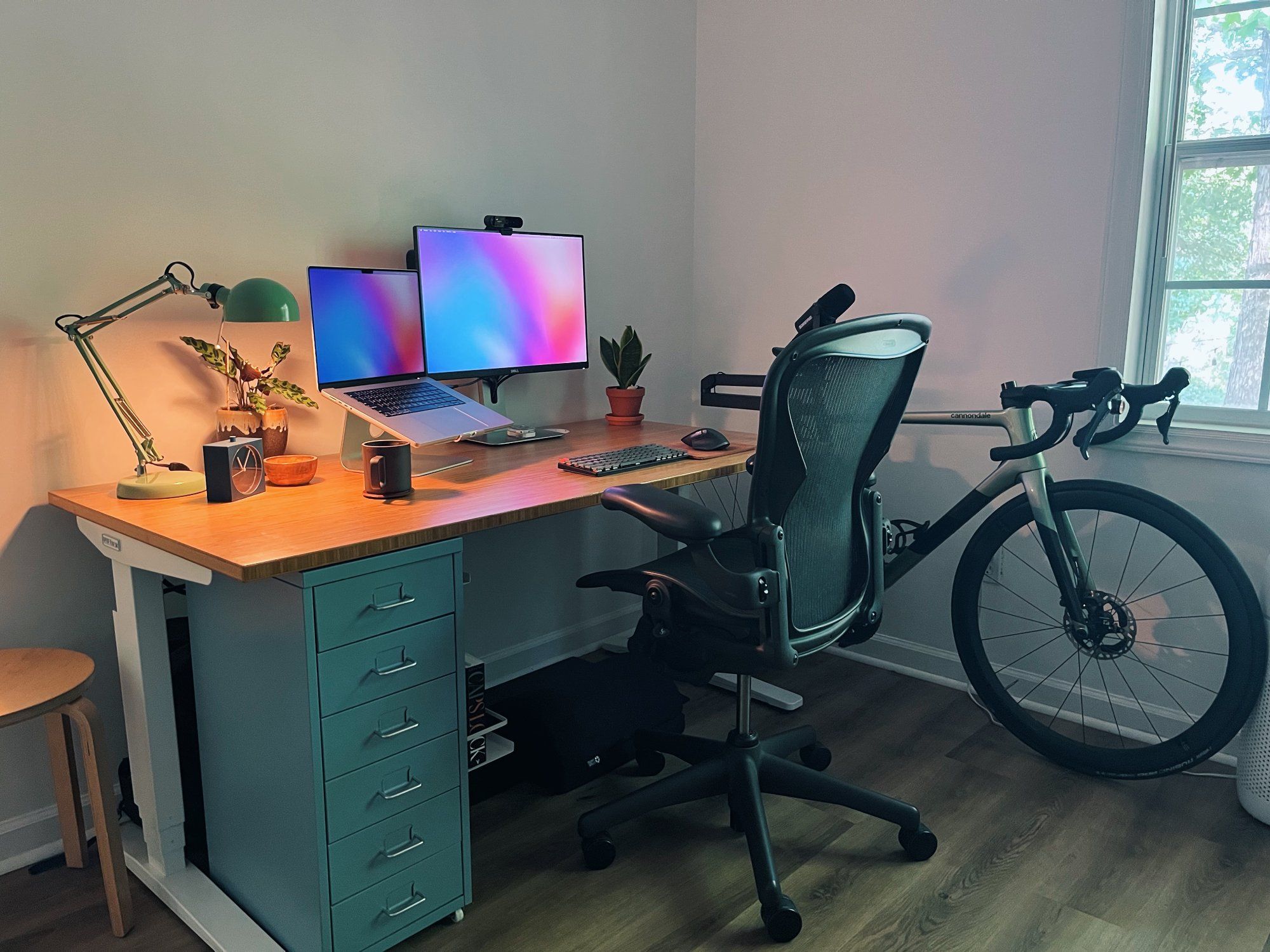 A minimal WFH standing desk setup with a bike by the window