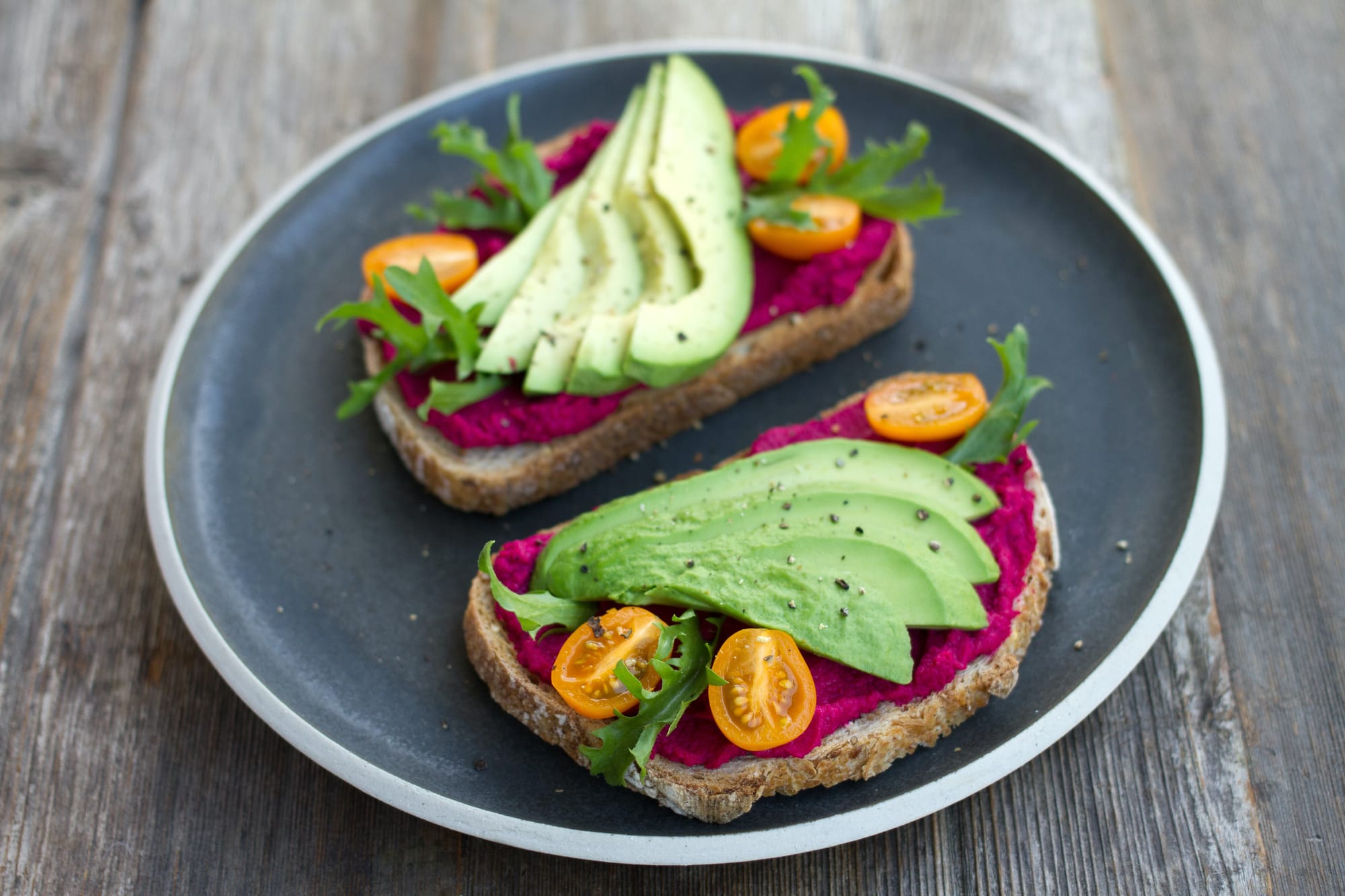 Two avocado and beetroot toasts with yellow cherry tomatoes