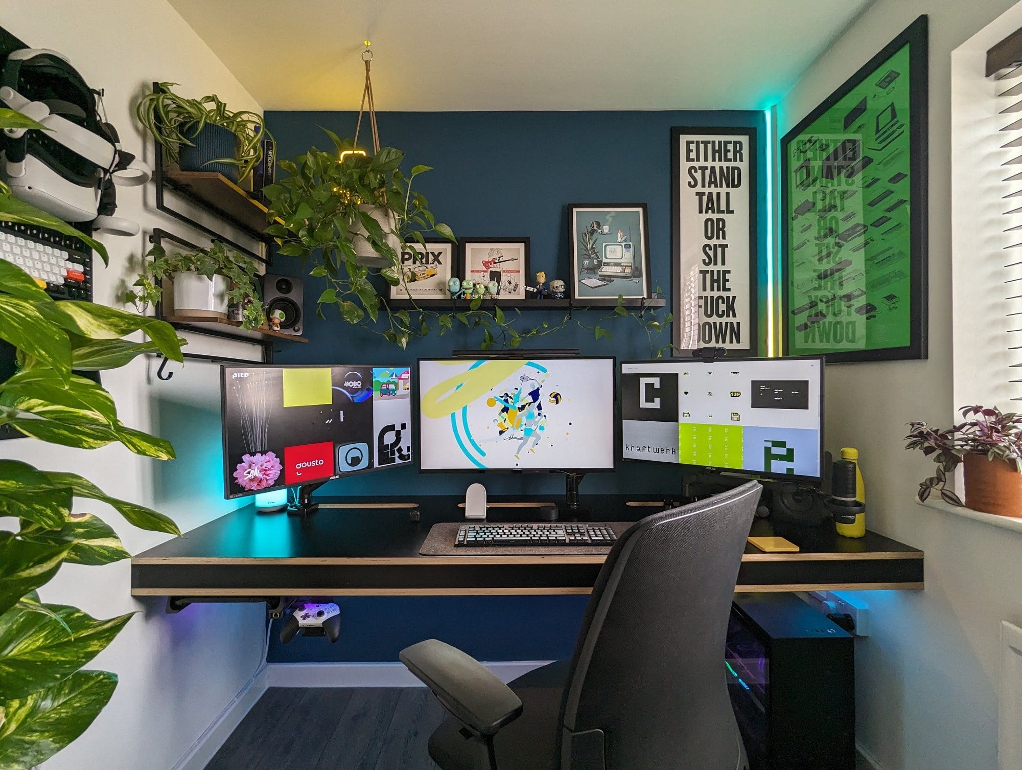 A modern home office setup featuring a sleek desk with a triple-monitor display, surrounded by lush green plants, framed artwork, motivational posters, and ambient LED lighting