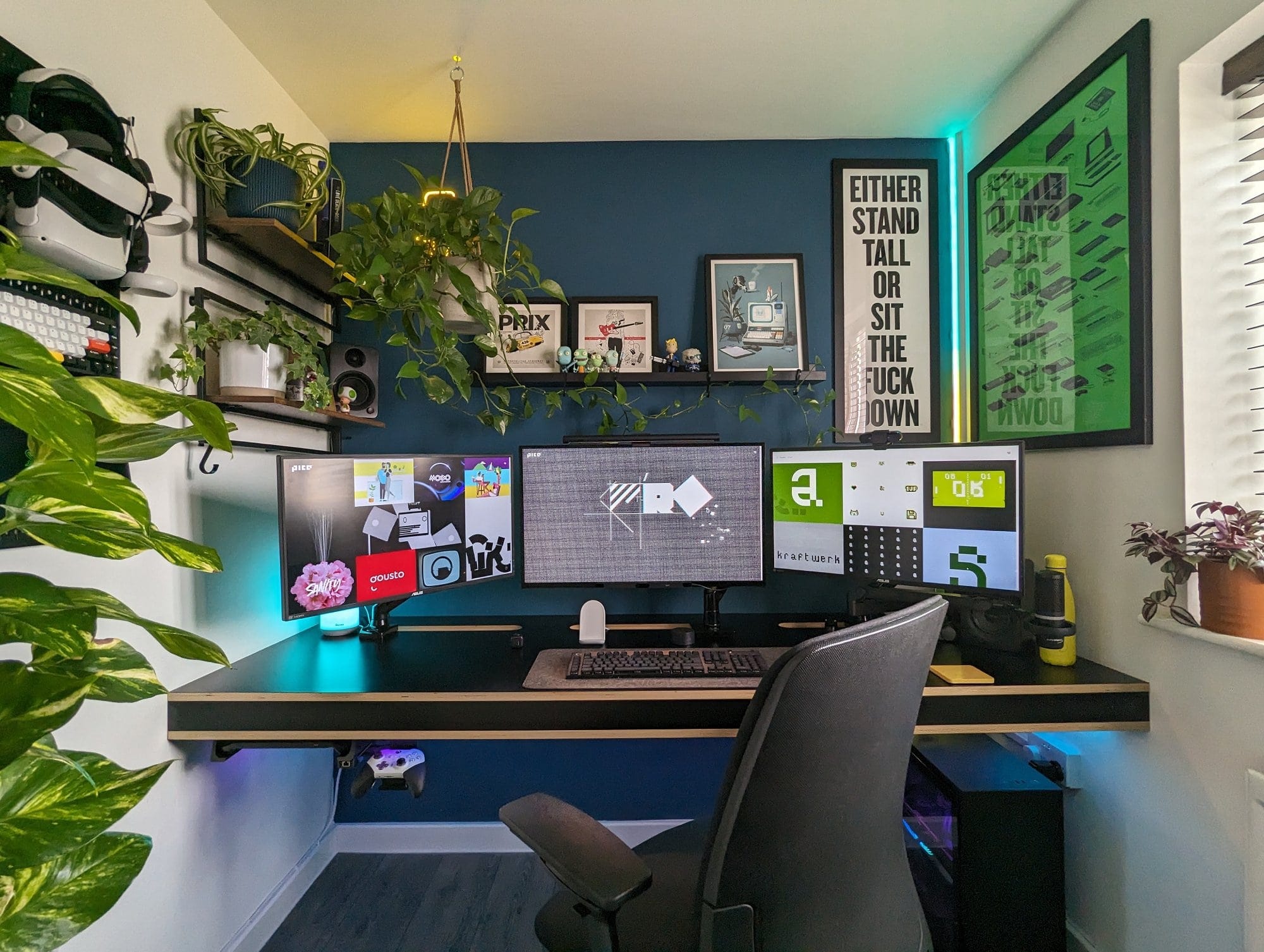 A modern home office setup with a triple-monitor computer desk, surrounded by lush green plants