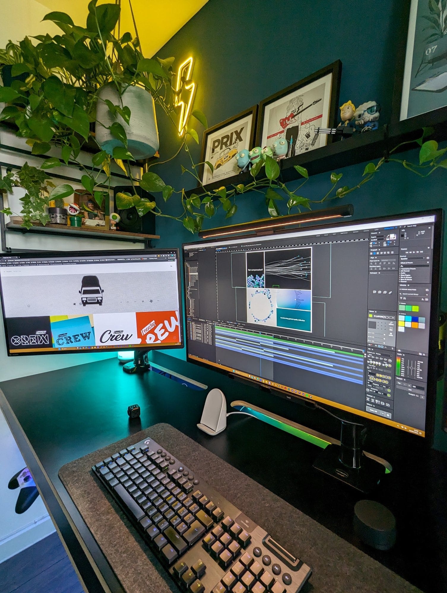 A modern home office desk setup featuring dual monitors, a mechanical keyboard, and a mouse, accented by lush green hanging plants, framed artwork, a neon lightning bolt light, and organised shelves with various decor items