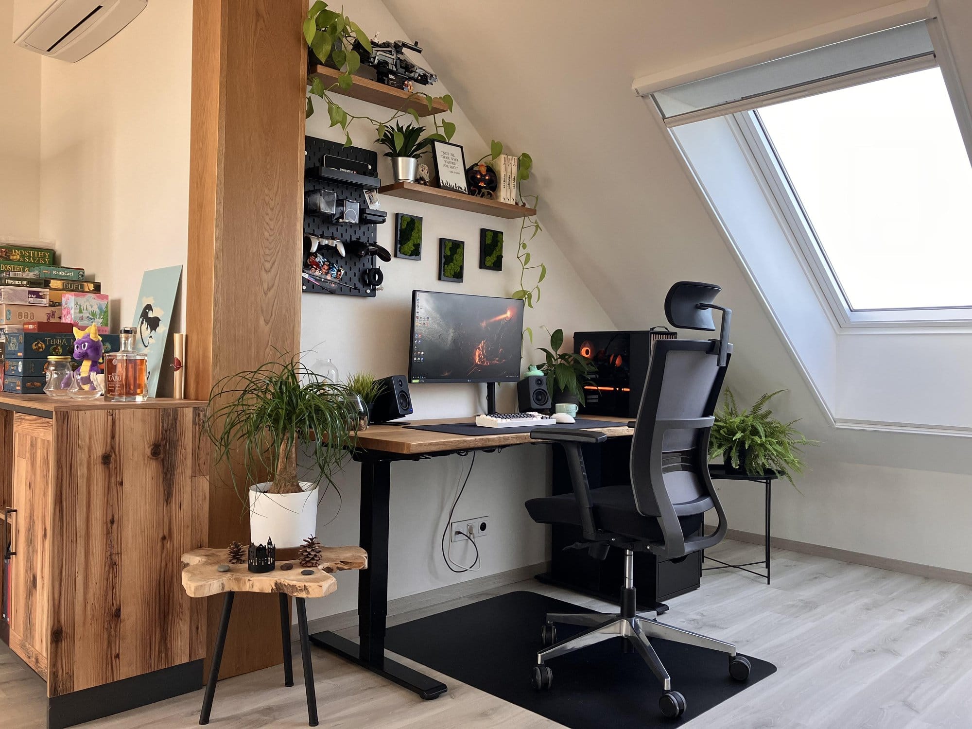 A modern home office setup with a wooden desk, ergonomic chair, multiple plants, and a large window providing natural light