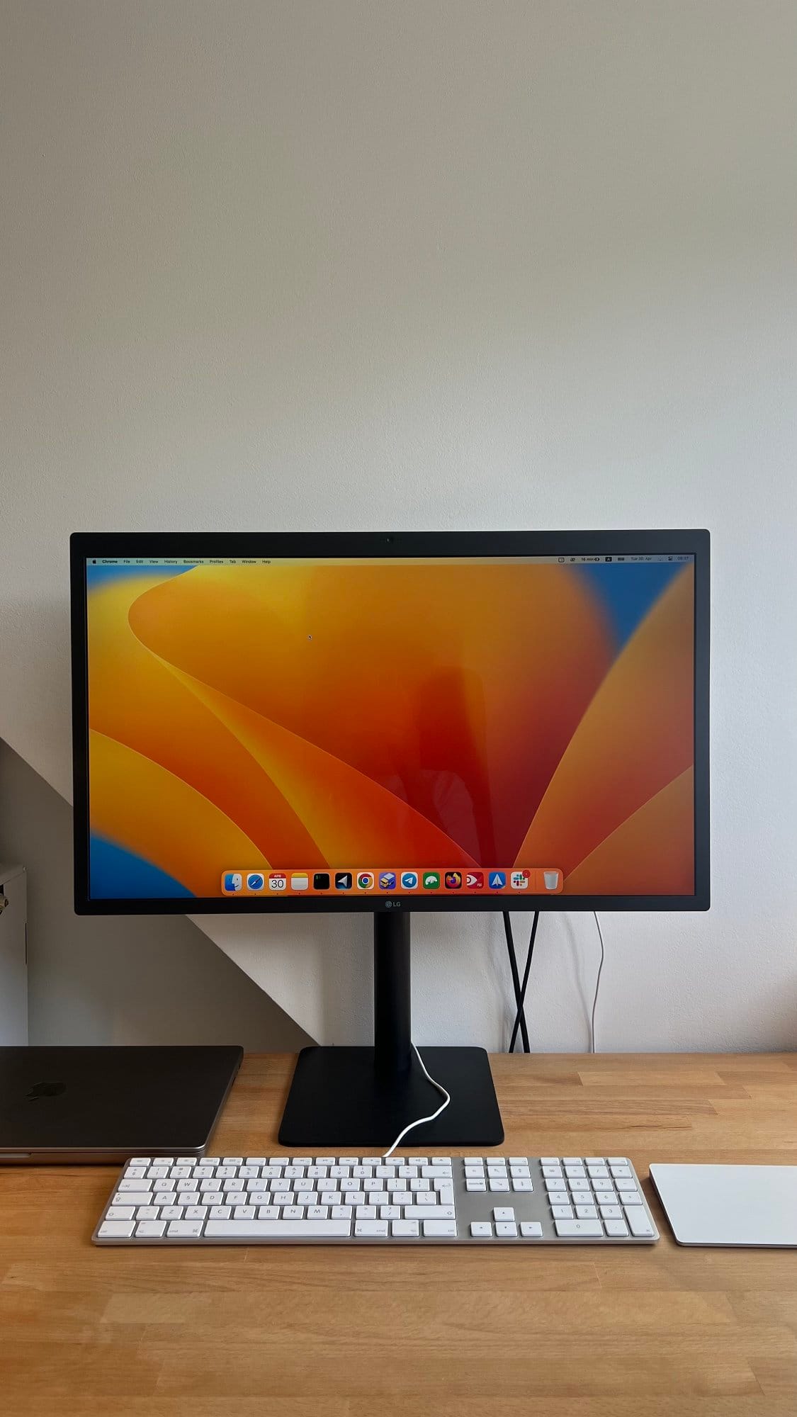 A minimalist home office setup featuring an LG UltraFine 5K monitor displaying a macOS desktop, a MacBook Pro M1 16″ 2021, an Apple Magic Keyboard, and an Apple Trackpad II, all arranged neatly on an IKEA GERTON tabletop