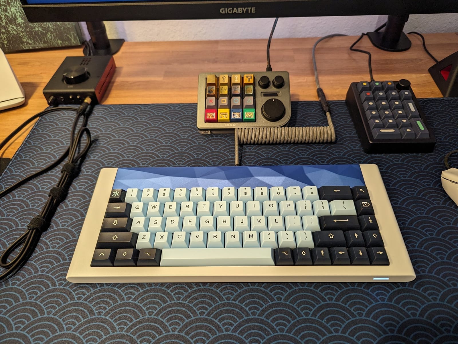 A neatly organised desk setup featuring a mechanical keyboard with grid 650 + KAT Mizu keycaps and Gazzew Boba U4T switches, dual monitors, headphones, a mouse, and various desk accessories