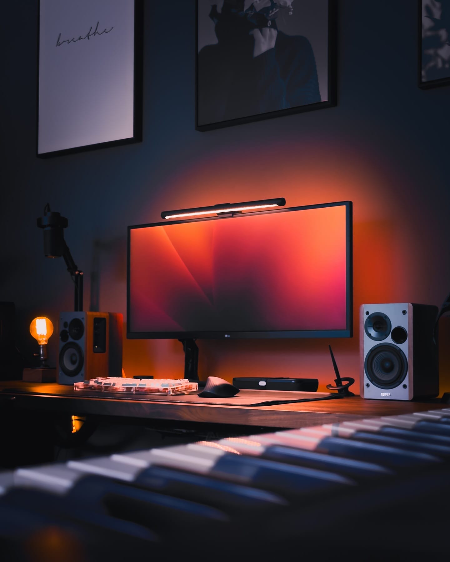 A stylish and dimly-lit workspace featuring an LG 34WK650 monitor on a Flexispot MA-8 mount, illuminated by a Xiaomi Light Bar, with a Switch Couture Frosted Acrylic Alice keyboard, Logitech MX Master 3 mouse, and Edifier R1280T speakers