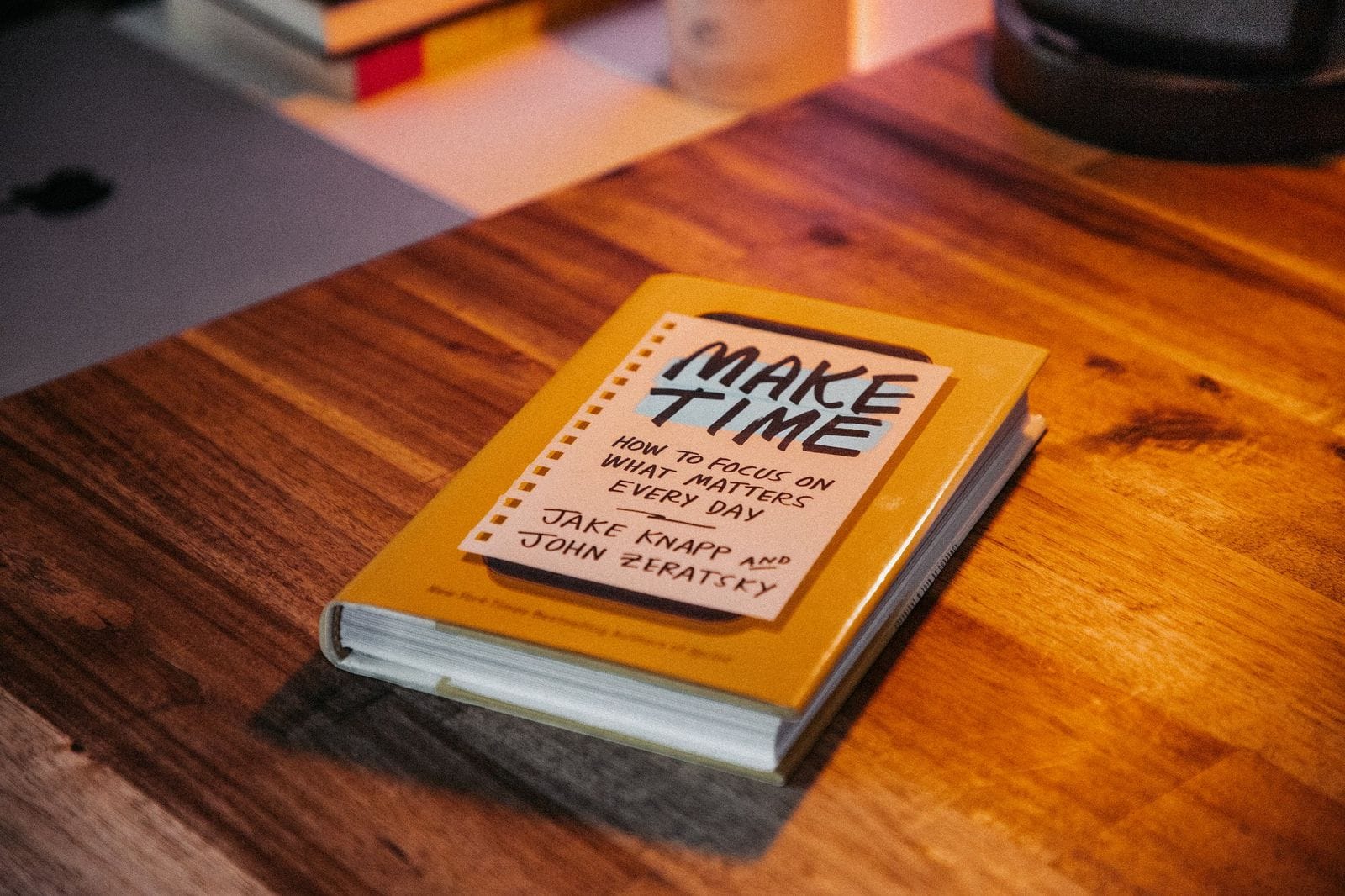 A book called Make Time: How to Focus on What Matters Every Day lying on a wooden desk