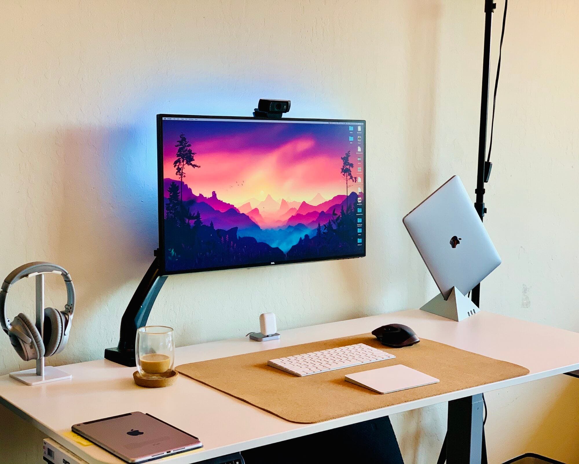 A simple desk setup with a monitor on an adjustable arm and a laptop on a custom stand