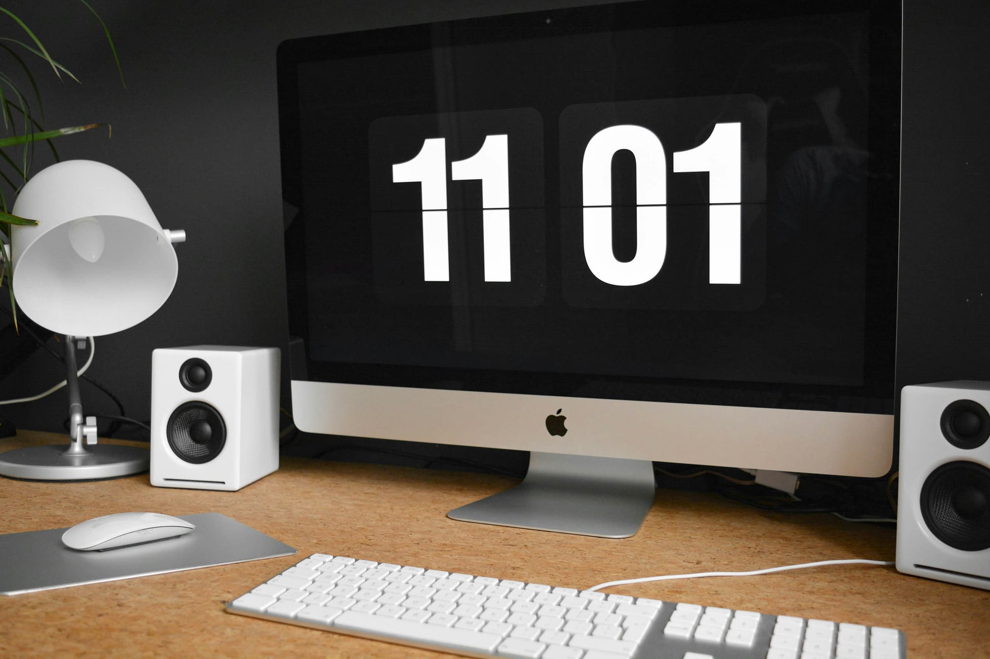 A modern desktop setup featuring an Apple computer displaying the time 11:01