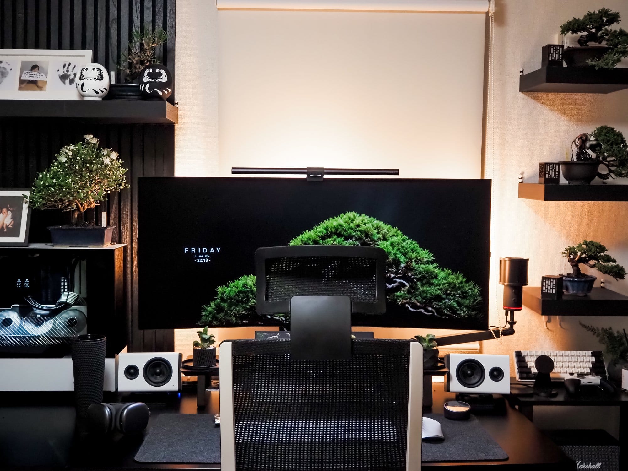 A stylish desk setup with a Corsair XENEON FLEX 45WQHD240 monitor, a BenQ ScreenBar, a white AIMchair office chair, white NZXT Relay speakers, bonsai trees, and Daruma dolls