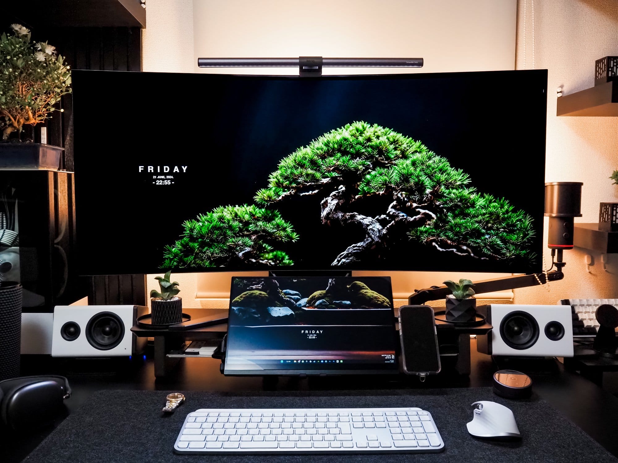 A modern desk setup featuring a Corsair XENEON FLEX 45WQHD240 monitor with a BenQ ScreenBar Halo light bar, and NZXT Relay speakers