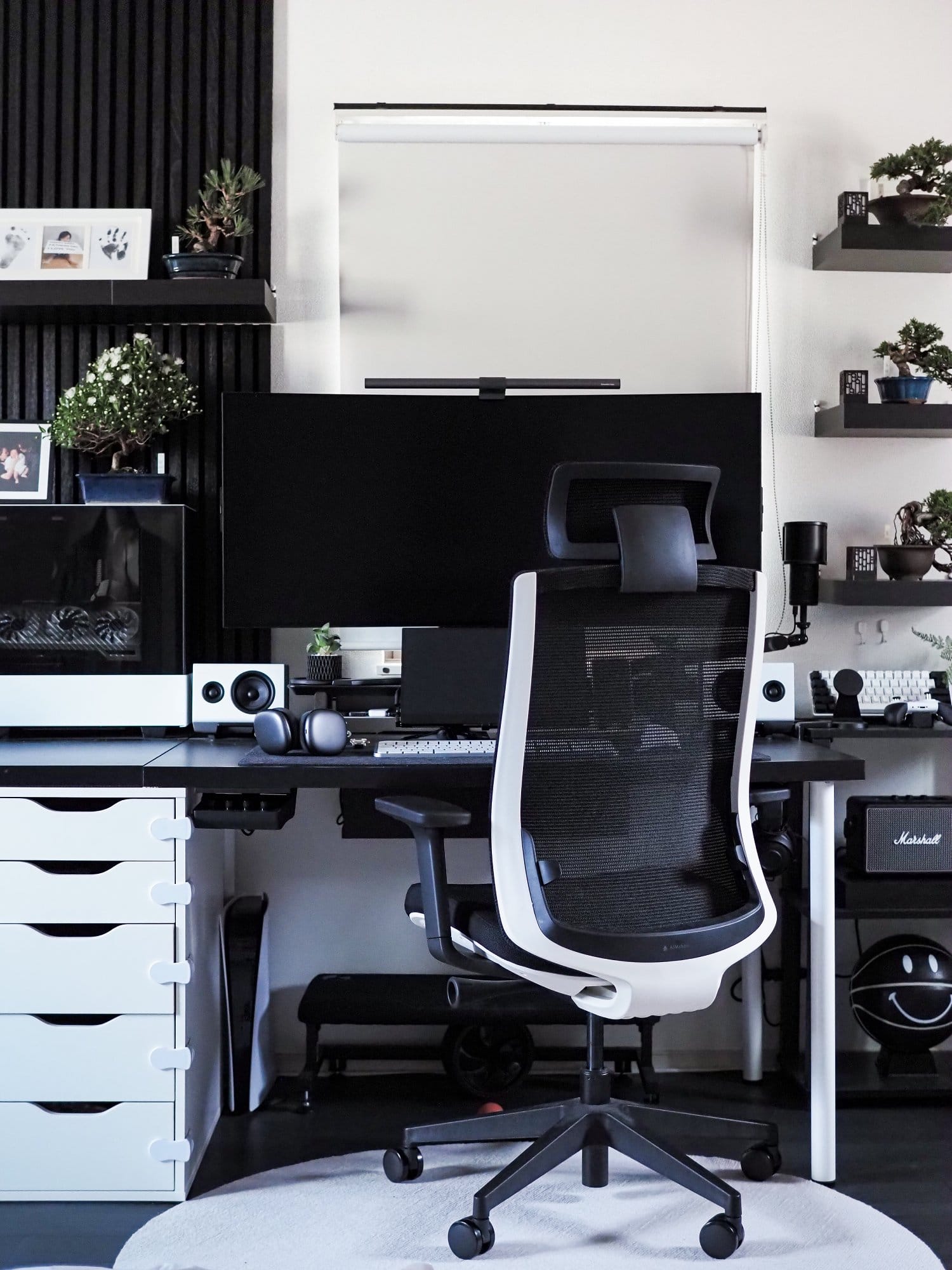 A clean and organised workspace with a white AIMchair office chair and several bonsai trees