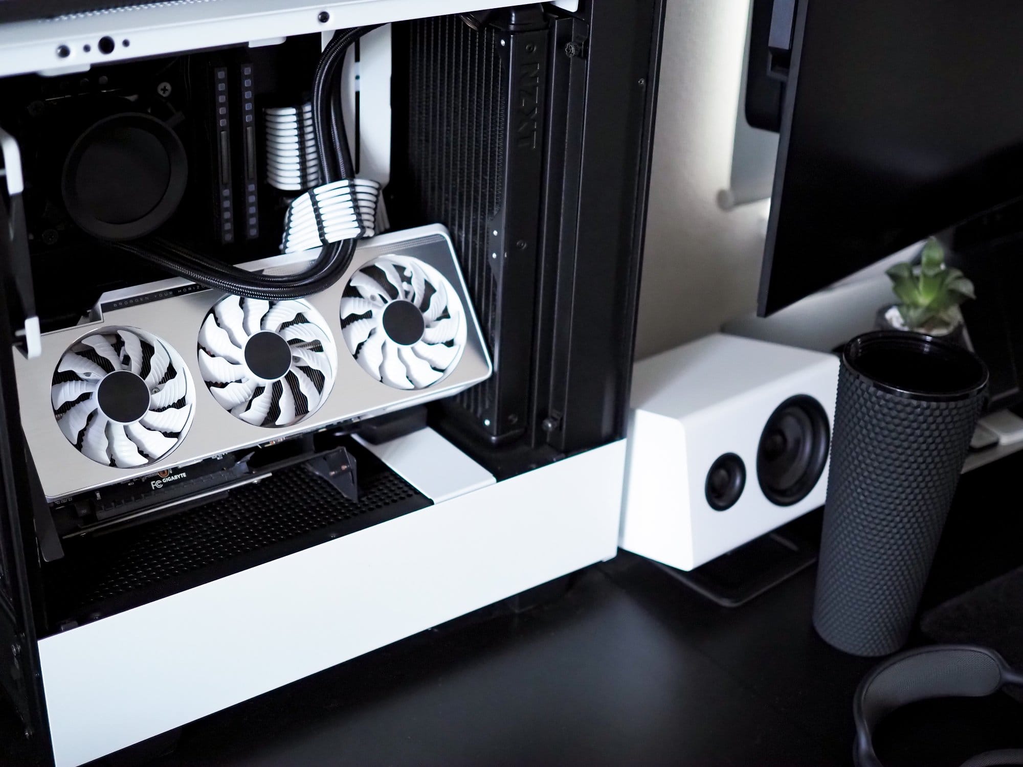 A close-up view of a high-performance PC setup featuring a GIGABYTE NVIDIA GeForce RTX 3090 GPU and white NZXT Relay speakers