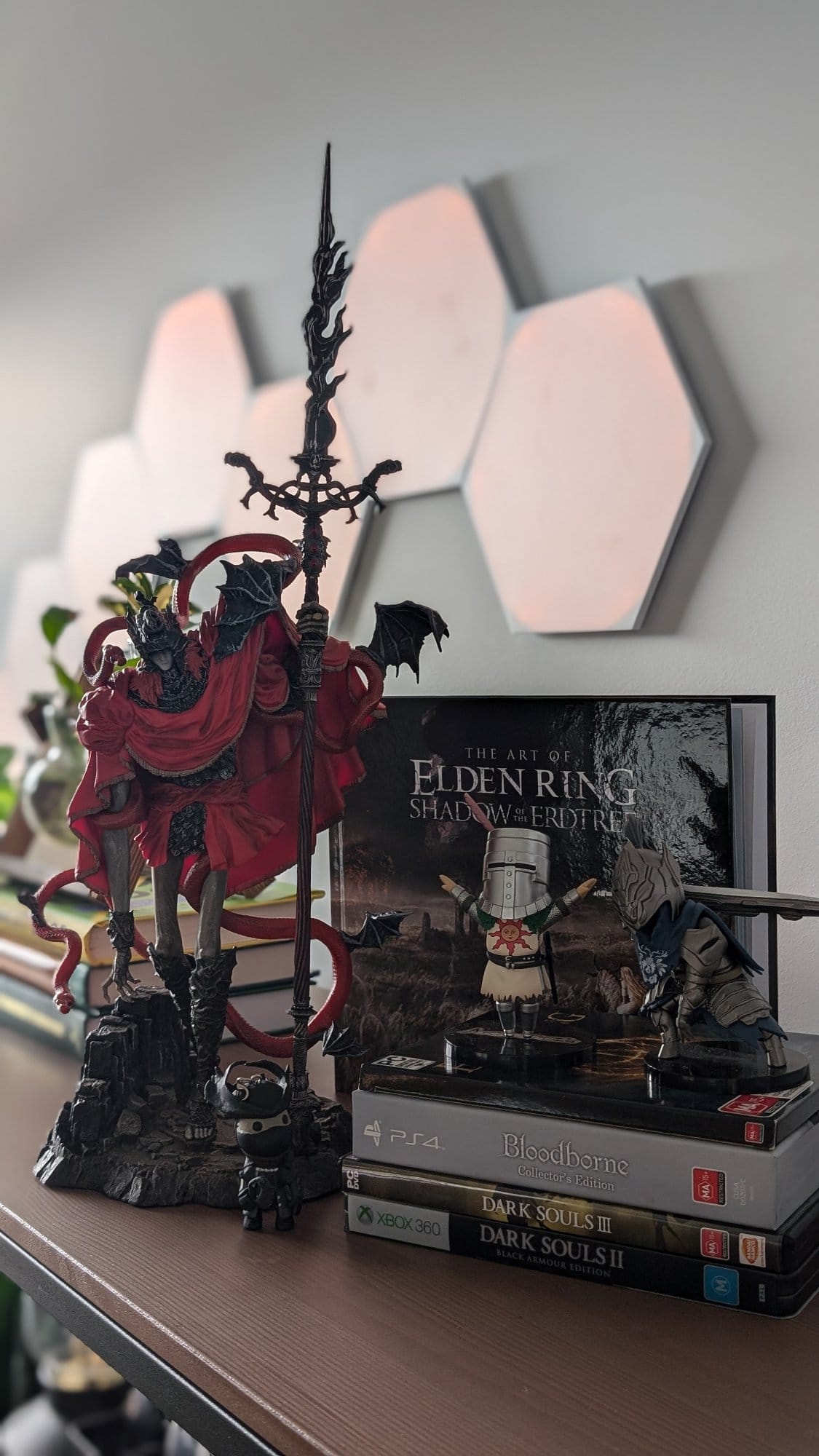 A dedicated display featuring intricately designed figures from the Soulsborne series, a collection of game cases including titles from Bloodborne and Dark Souls, and ‘The Art of Elden Ring: Shadow of the Erdtree’ book