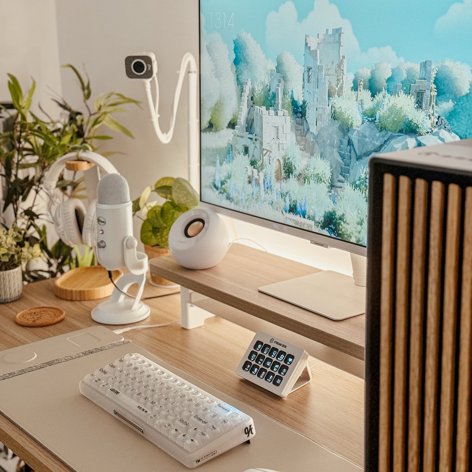 A well-organised home workspace with a Samsung M7 monitor, Logitech Blue Yeti in White Mist microphone, and Creative Pebble speakers, enhanced by a LoFree 1% Misty keyboard and a Logitech StreamCam, set on a Vernal-UK standing desk with a matching monitor stand