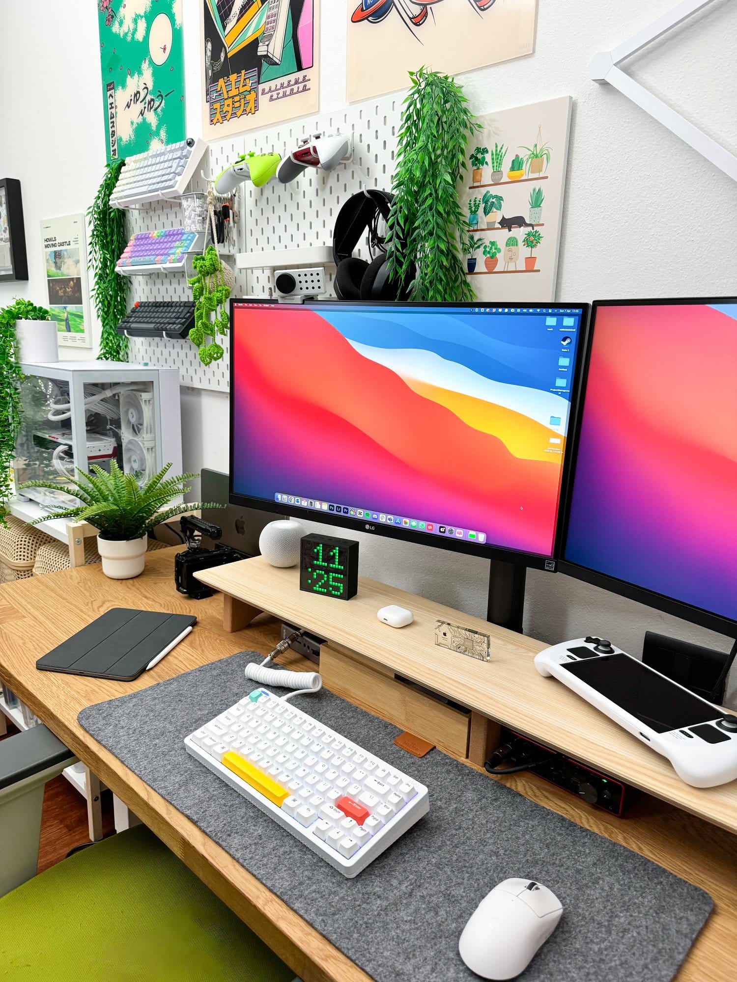 A dual-monitor desk setup featuring LG 27UN880P monitors, a NuPhy Halo keyboard, Logitech G Superlight Pro mouse on a Harber London wool-like desk mat, a glowing PC setup with Radeon 7900XTX external GPU, and decorative elements including vibrant wall art, green plants, and geometric LED wall lights, complemented by a MacBook Pro M1 Pro 2022, Focusrite audio card, various tech accessories, and an iPad