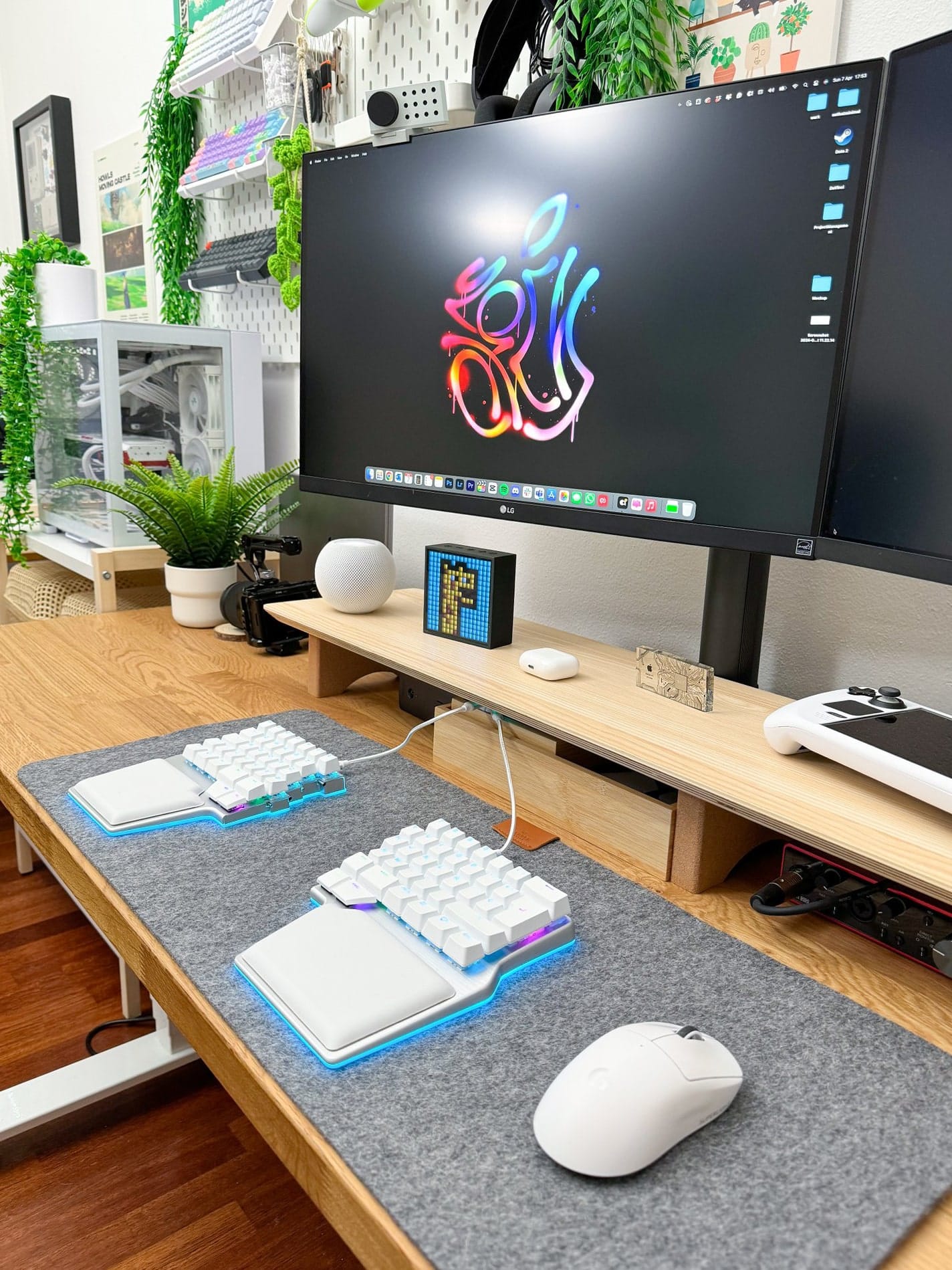 A well-organised desk setup with an LG 27UN880P monitor, NuPhy Halo split keyboard, Logitech G Superlight Pro mouse on a Harber London wool-like desk mat, MacBook Pro M1 Pro 2022, Focusrite audio card, and a decorative bonsai, all arranged on an IKEA KARLBY tabletop with Flexispot legs, complemented by colourful wall art and various tech accessories on a pegboard