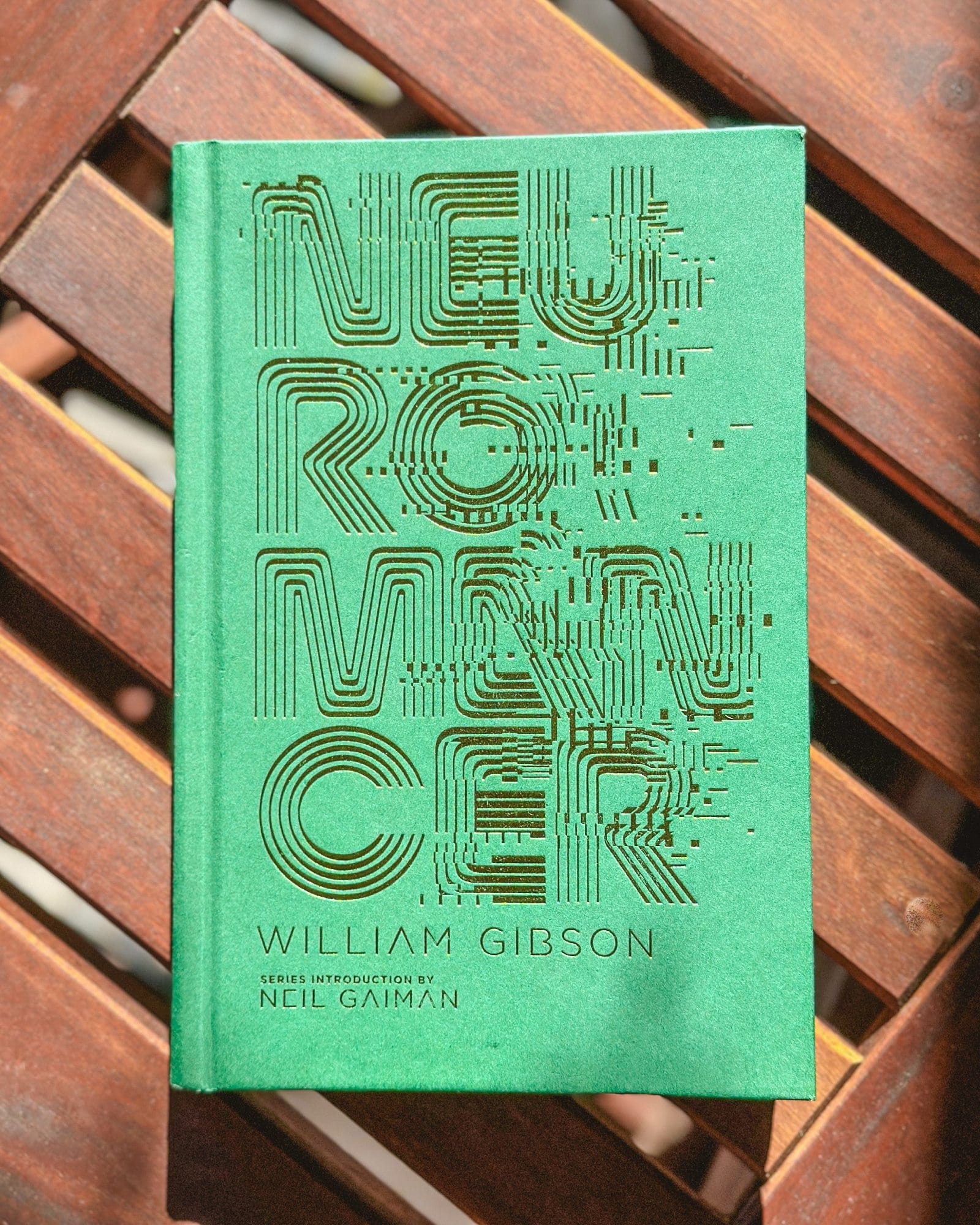 A close-up of a special edition of William Gibson’s Neuromancer, featuring a green cover with futuristic typography and an introduction by Neil Gaiman