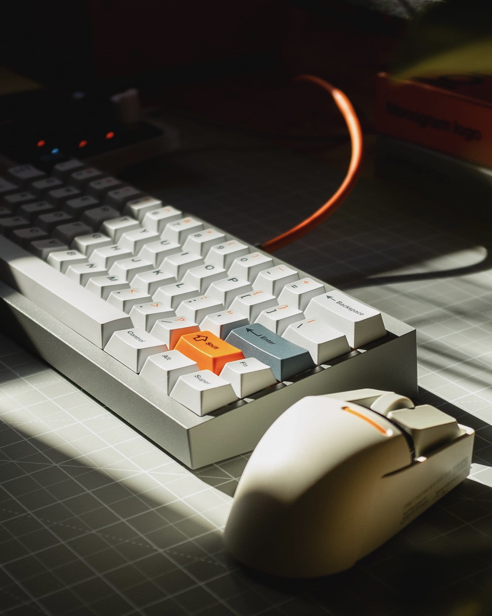 A close-up of a custom-built keyboard with white and orange keys, paired with a Touch PBT Wireless Mouse