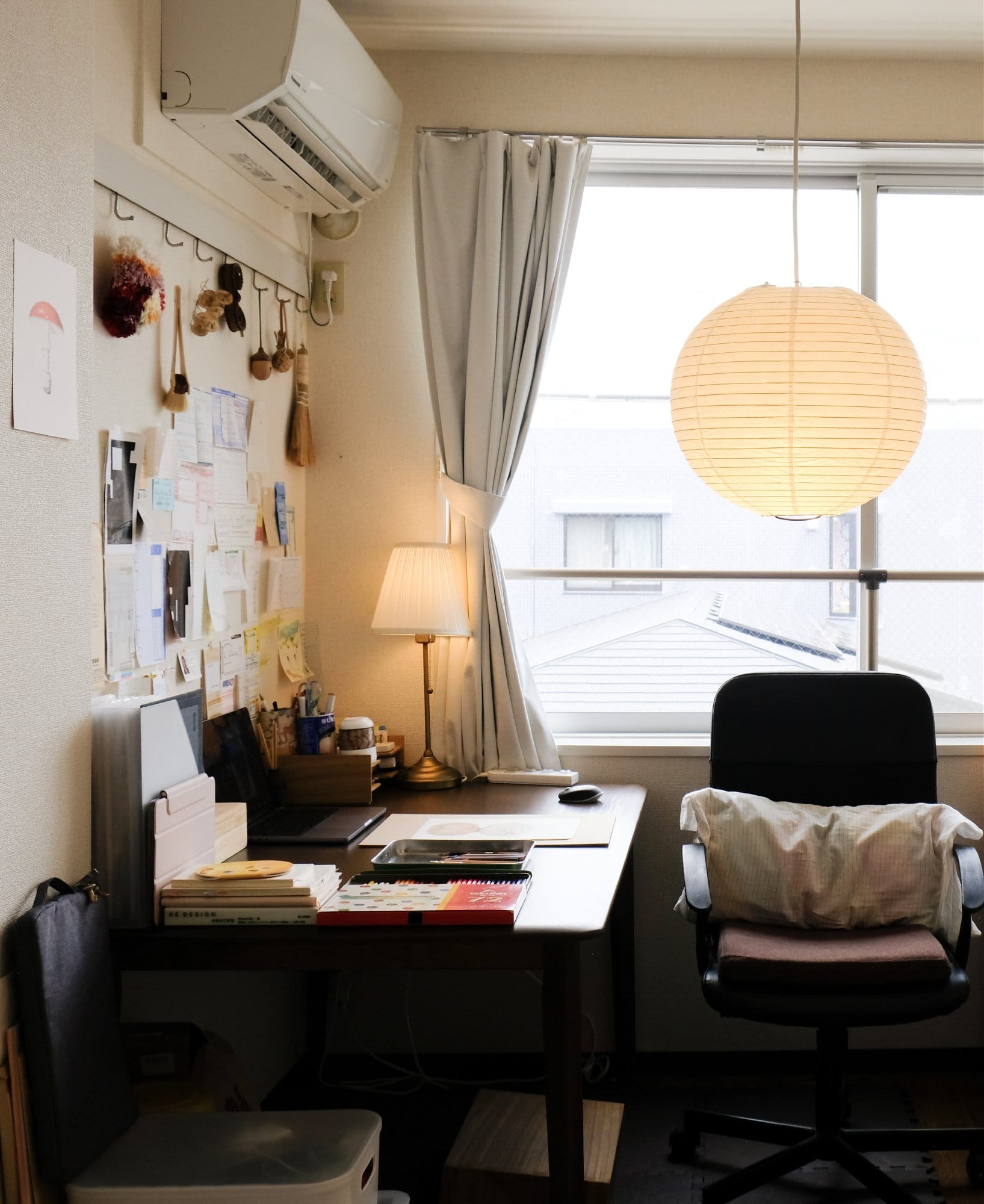 A cosy and minimalist workspace with a laptop, MUJI wooden letter tray, and an IKEA ÅRSTID lamp on a small desk