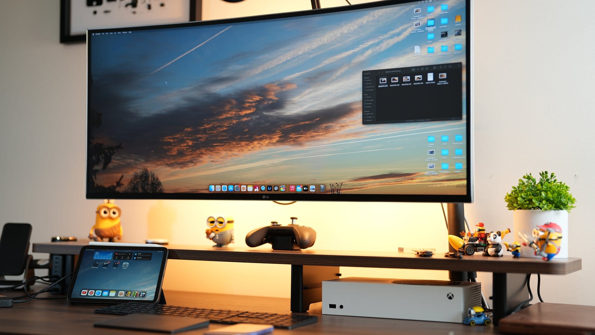 A home office setup showing an LG 38WN95C-W monitor on a Vivo Arm, a MacBook Pro, and an Xbox Series S on a Vernal desk shelf, with a gaming controller and small desk decorations