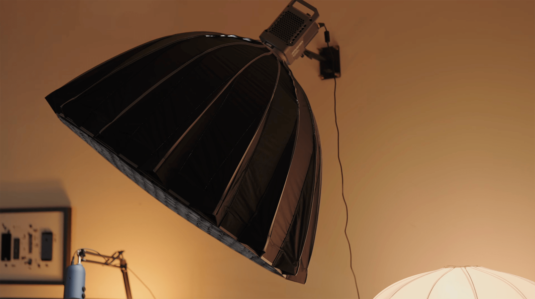 A close-up of a large overhead studio light with a black Aputure reflective dome