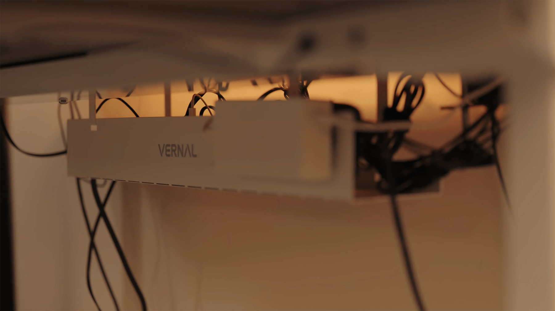 A close-up of a cable management tray under a desk, labelled “Vernal,” with various cables neatly organised inside