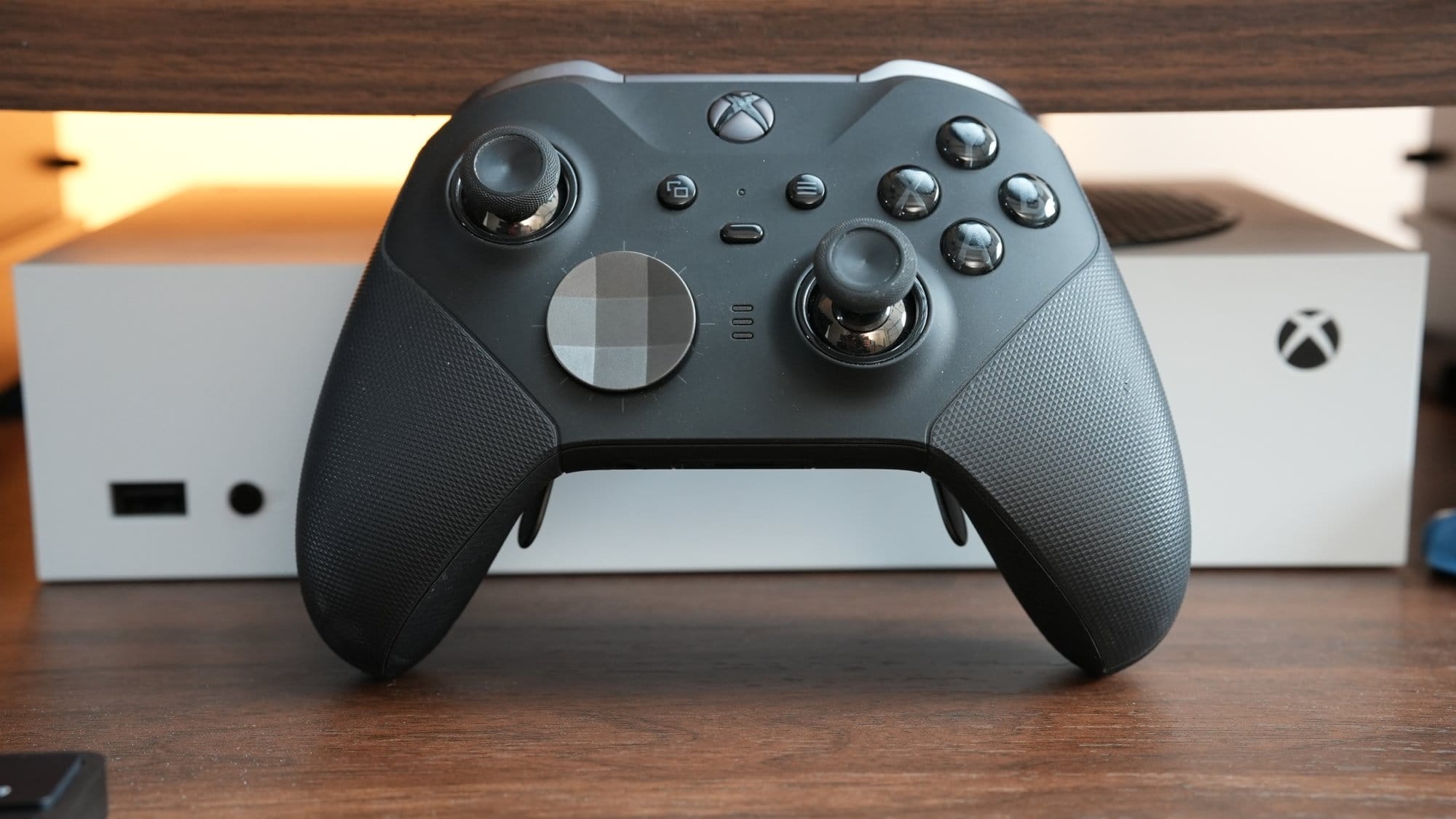 A close-up of an Xbox Elite controller placed in front of an Xbox Series S console