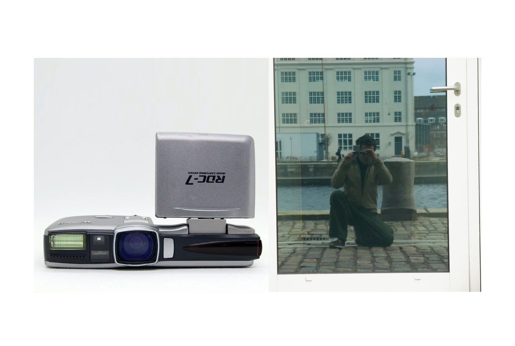 This image shows a Ricoh RDC-7 camera on the left side, with its distinct flip-up LCD screen visible. On the right, a reflection of a person crouching and taking a photo with the same camera is captured in a glass door or window, with a waterfront and buildings in the background