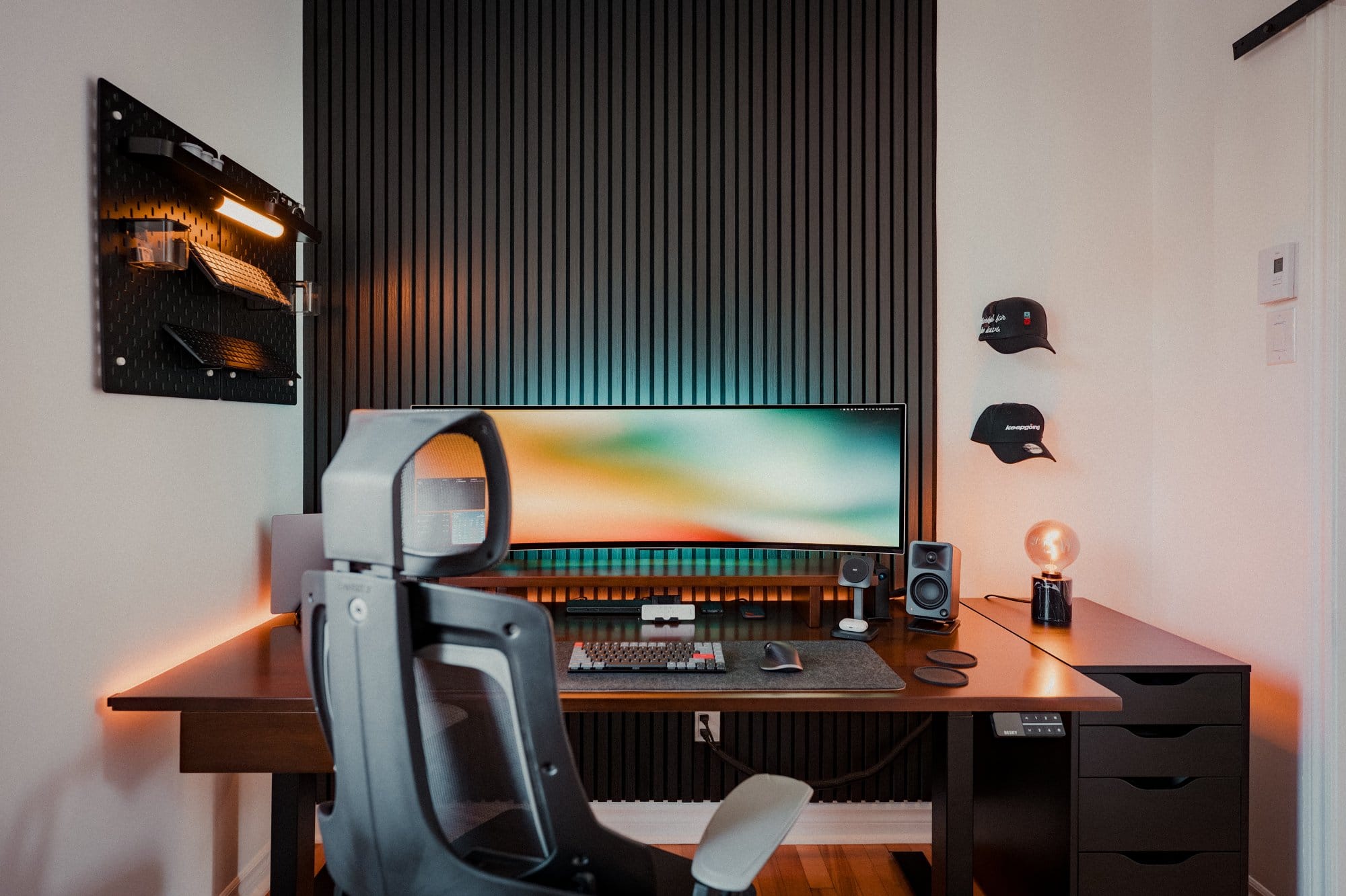 A home office setup with a Samsung 49″ Odyssey OLED G9 monitor, Desky Pro+ ergonomic chair, Kanto ORA Reference Desktop Speakers, and an IKEA SKÅDIS pegboard on the wall