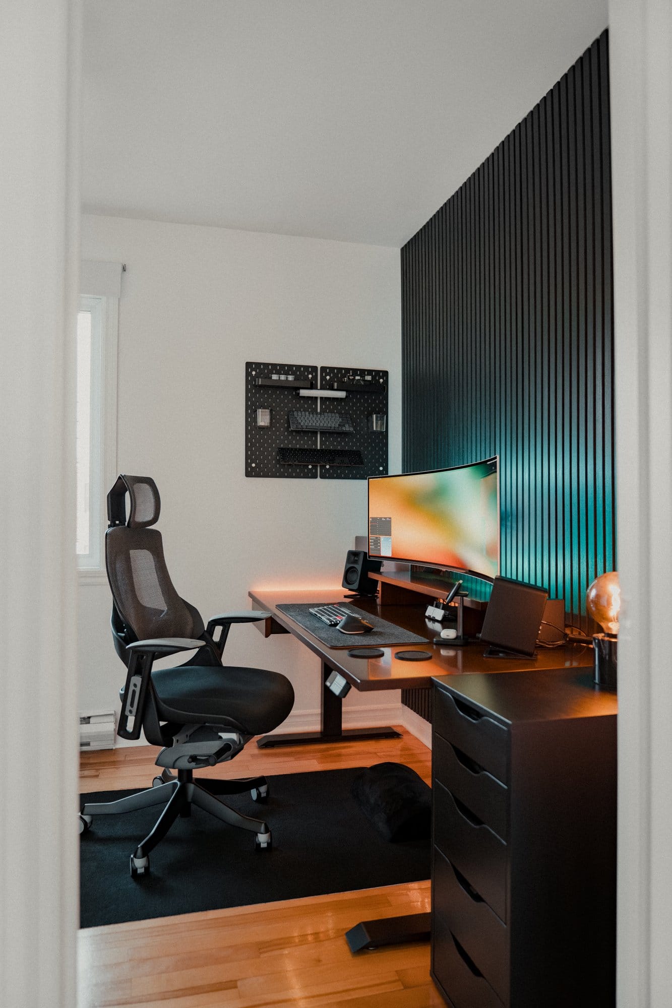 A home office setup with a Samsung 49″ Odyssey OLED G9 monitor, Desky Pro+ ergonomic chair, Kanto ORA Reference Desktop Speakers, and an IKEA SKÅDIS pegboard mounted on the wall