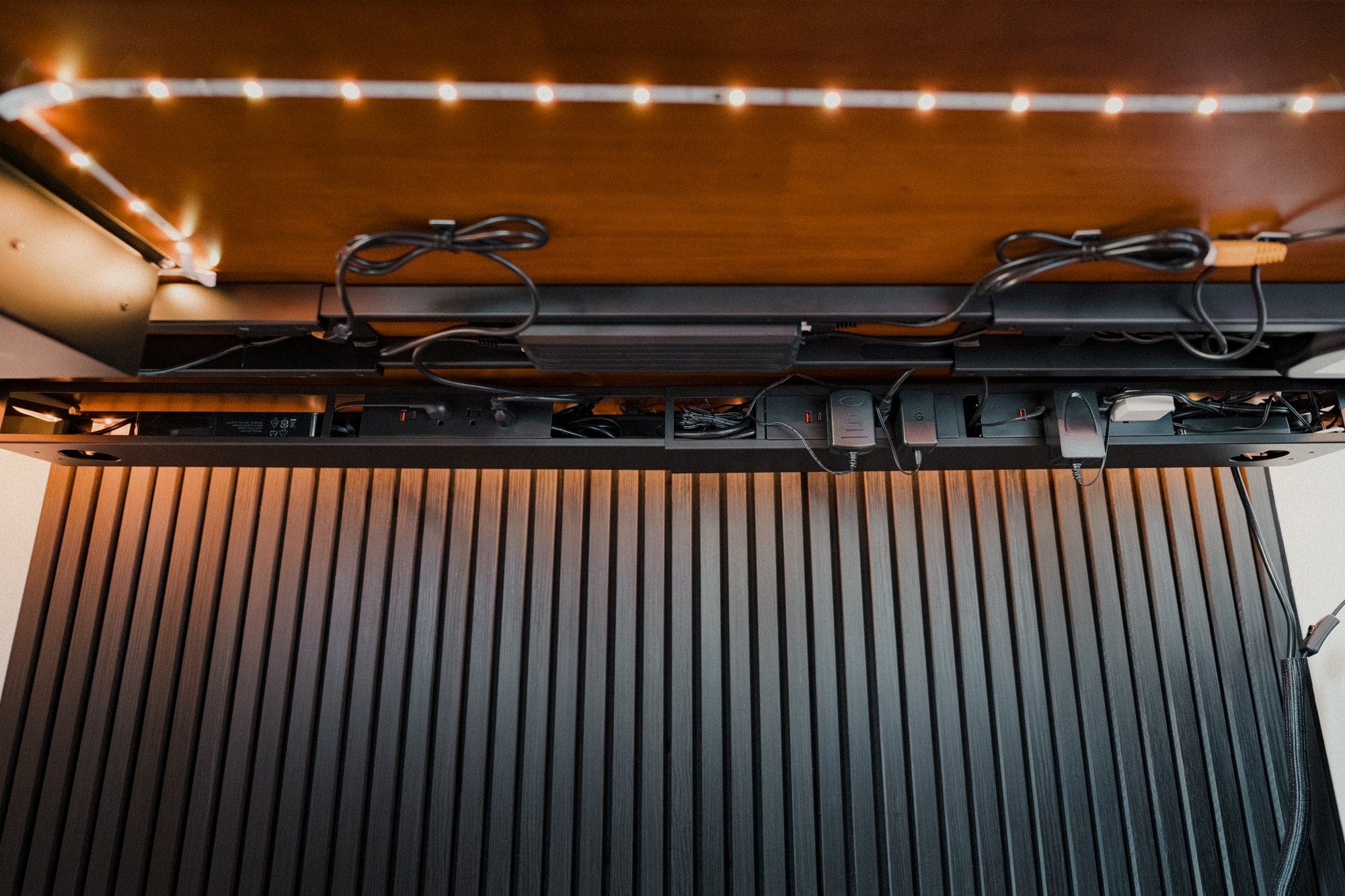 An under-desk view showing cable management, power strips, and Govee RGBIC LED strip lights