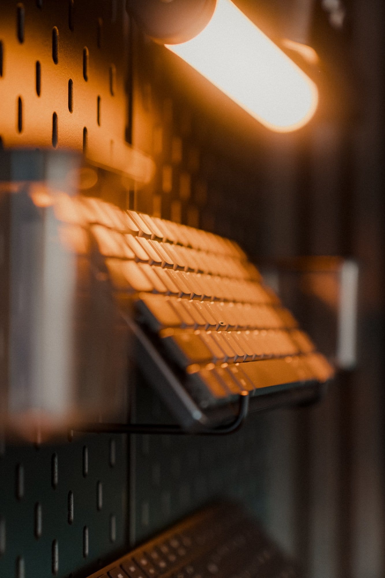 Close-up of a keyboard stored on an IKEA SKÅDIS pegboard, illuminated by a mounted LED light