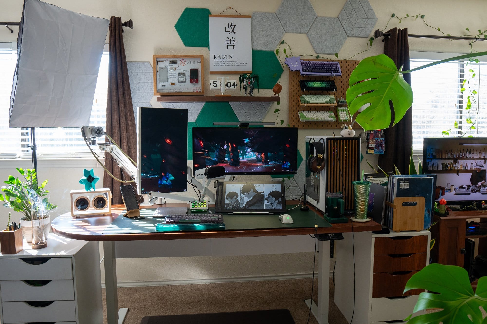 A home office desk setup with multiple monitors and hexagonal acoustic panels on the wall