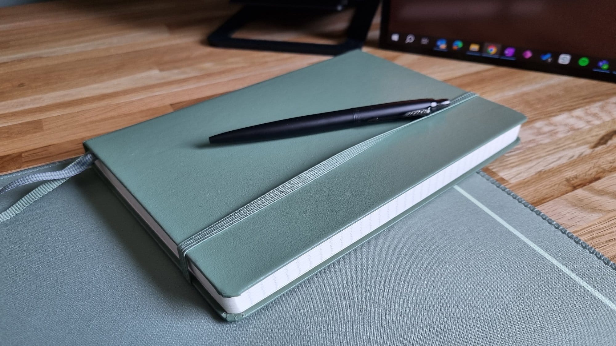 Close-up of a closed notebook with an elastic band, with a pen placed on top