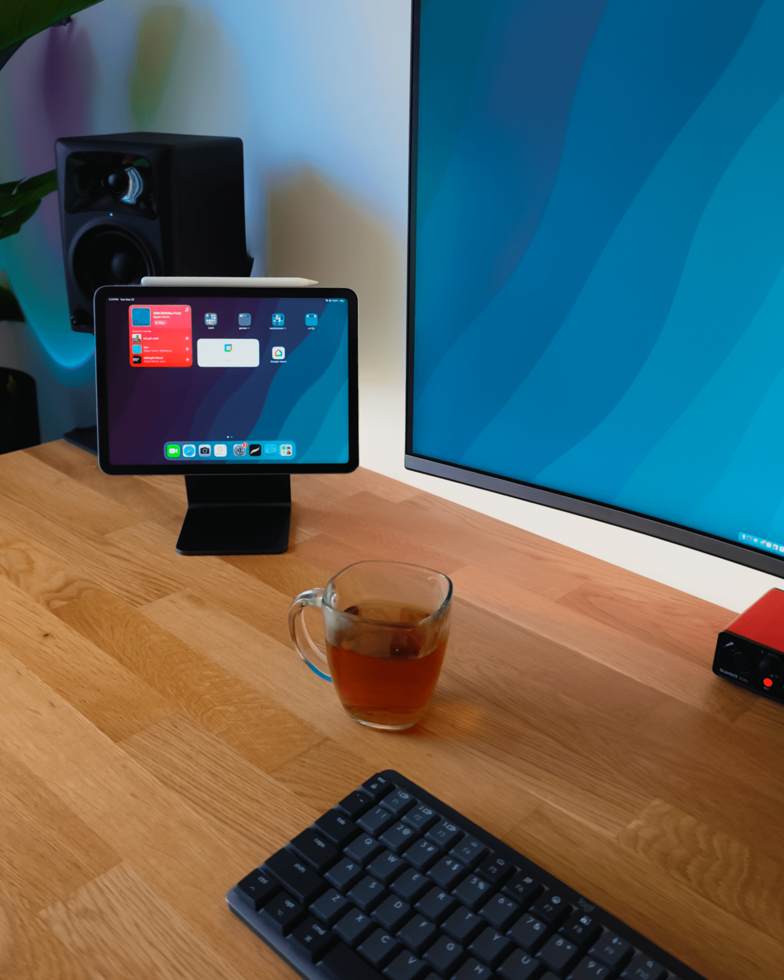 An iPad Air on an Elago Stand sits next to a Samsung LU32R590CWNXZA monitor, with a Logitech MX Mechanical Mini keyboard and a cup of tea on an IKEA KARLBY oak desk