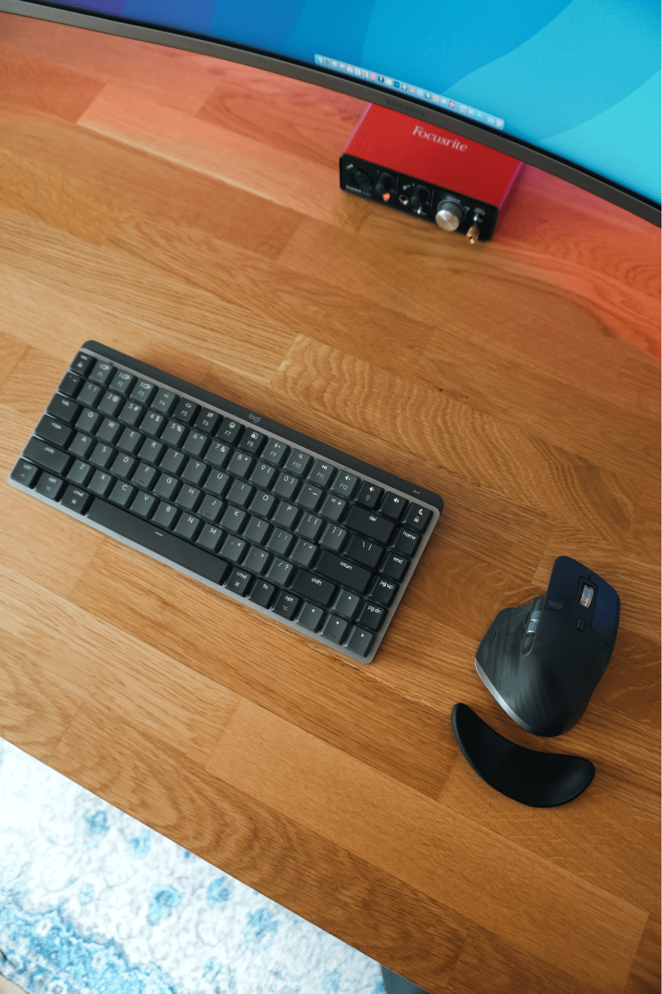  A Logitech MX Mechanical Mini keyboard and MX Master 3S mouse on an IKEA KARLBY oak desk, with a Focusrite audio interface and Samsung LU32R590CWNXZA monitor in view