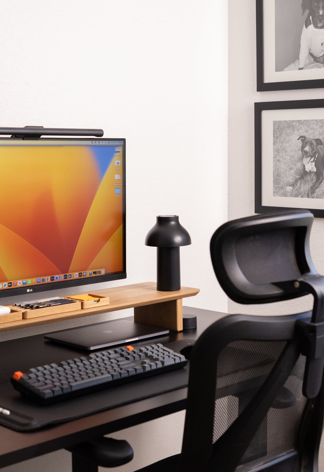 A desk setup with an LG UltraFine display, Keychron keyboard, Modhaus desk shelf, Hay PC portable lamp, and framed dog portraits on the wall