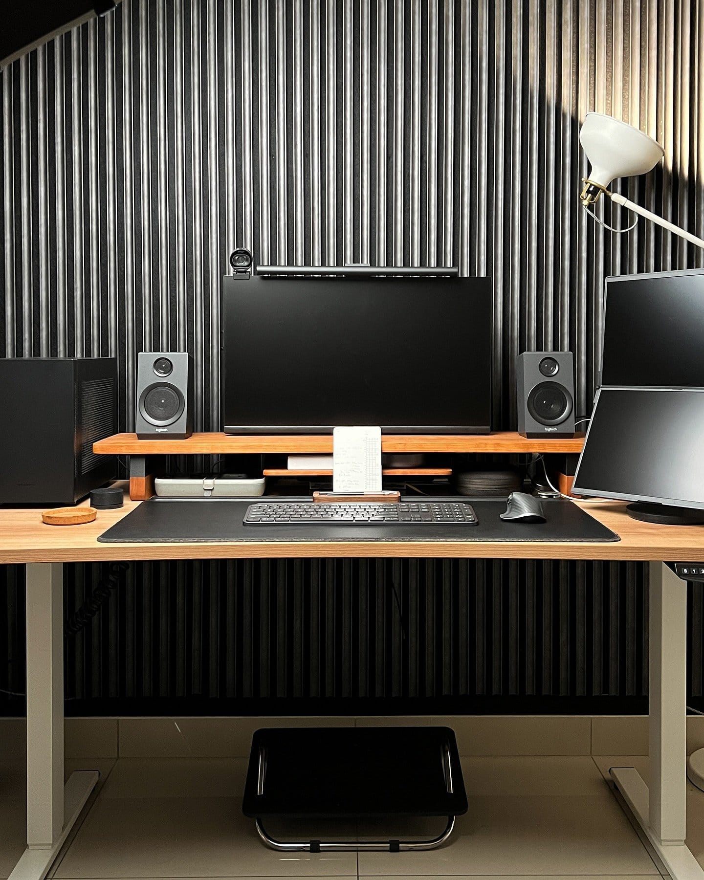 A desk setup with a monitor equipped with a BenQ Screenbar Halo, Logitech MX Keys keyboard, Logitech MX Master 3 mouse, and dual speakers on a Lone Birch desk shelf, all set on a Tyyli standing desk against a Reforma acoustic panel wall