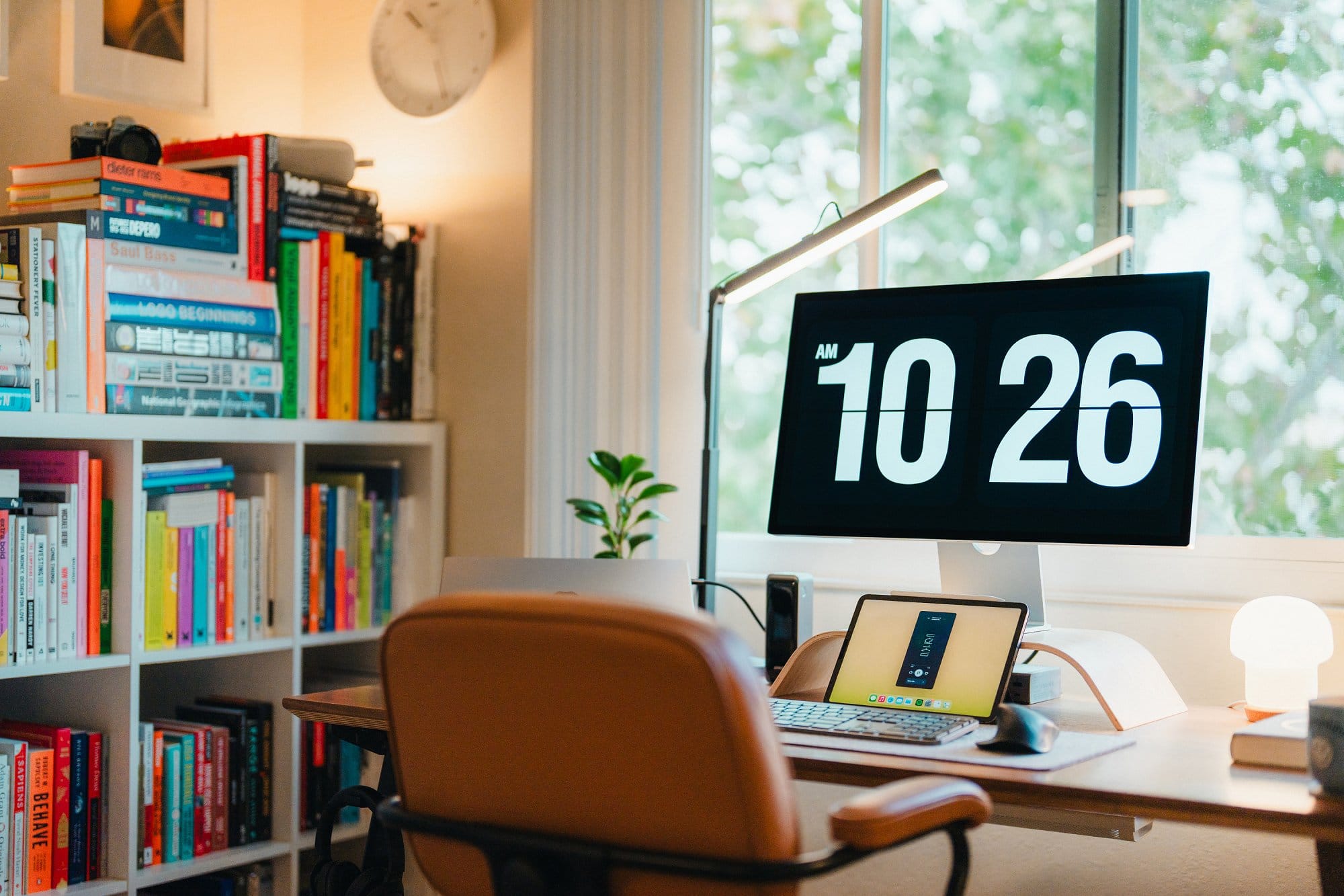 An IKEA ALEFJÄLL chair positioned at a Floyd table, with an Apple Studio Display, a Logitech MX Master 3 mouse, an iPad Pro on a Twelve South Curve stand, and a Logitech Litra Beam desk lamp