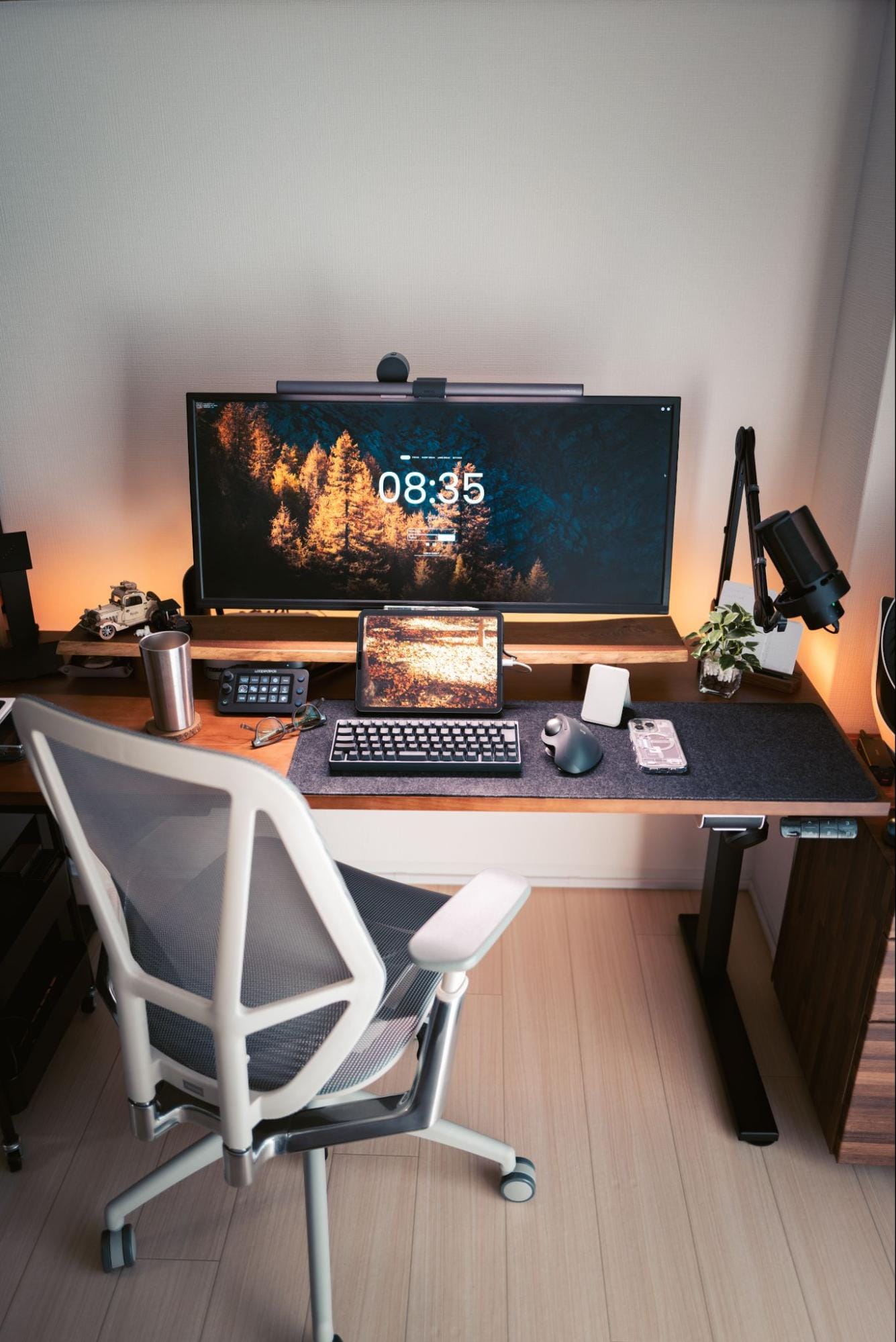 A home desk setup with a JAPANNEXT JN-VG34100UWQHDR monitor illuminated by a BenQ ScreenBar Halo, an iPad Pro 11″ 2021, a HHKB Professional HYBRID Type-S keyboard, a Logitech MX ERGO S mouse, and a Palmwork chair