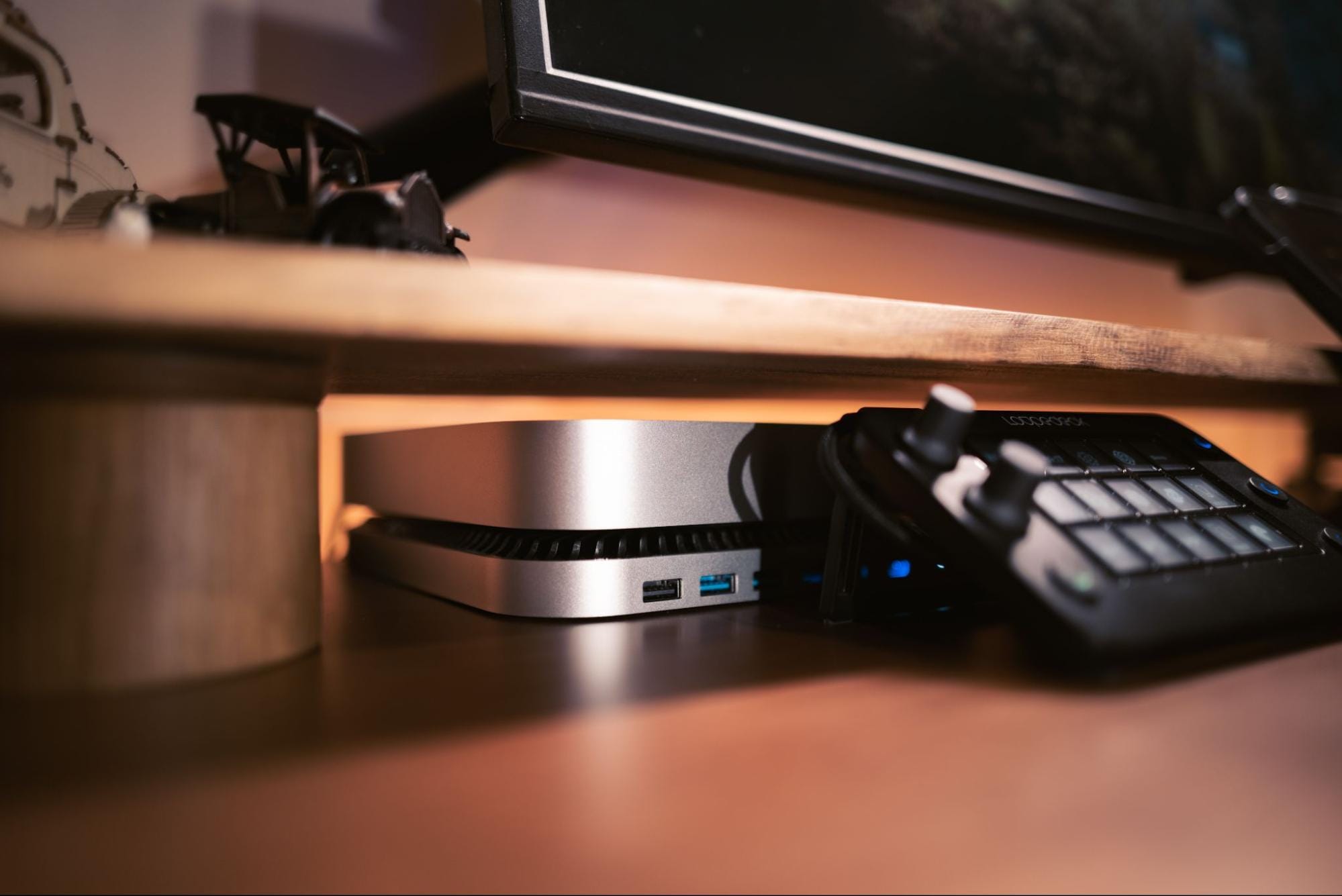 An Apple Mac mini under a desk shelf