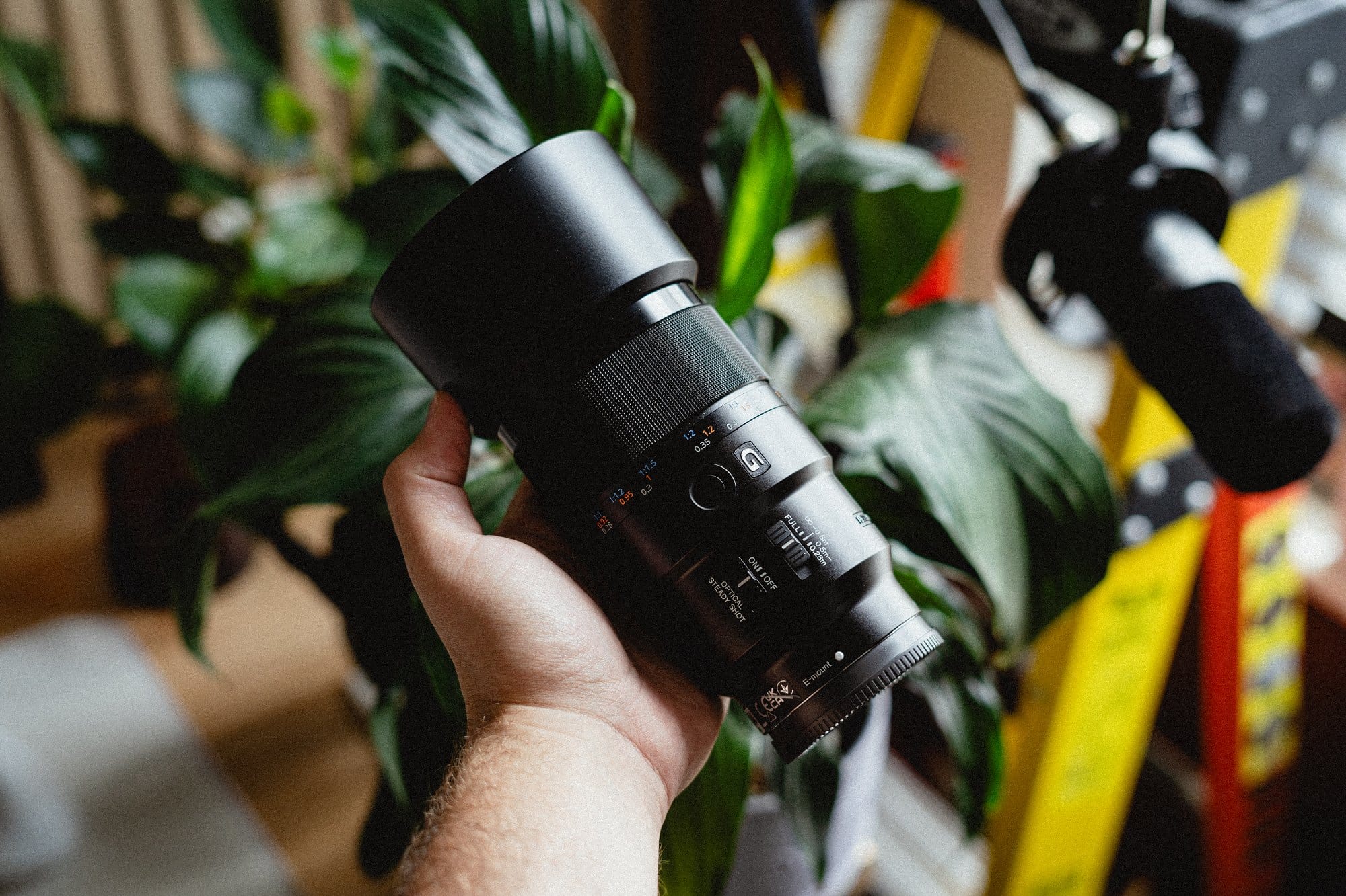  A hand holding a Sony 90mm f/2.8 Macro G OSS lens