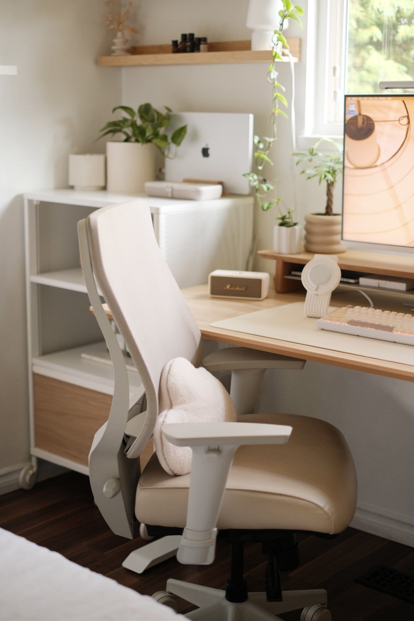 A desk area with an Ergonofis YouToo ergonomic chair, a MacBook Pro on a side cabinet, and a beige Marshall Emberton 2 speaker