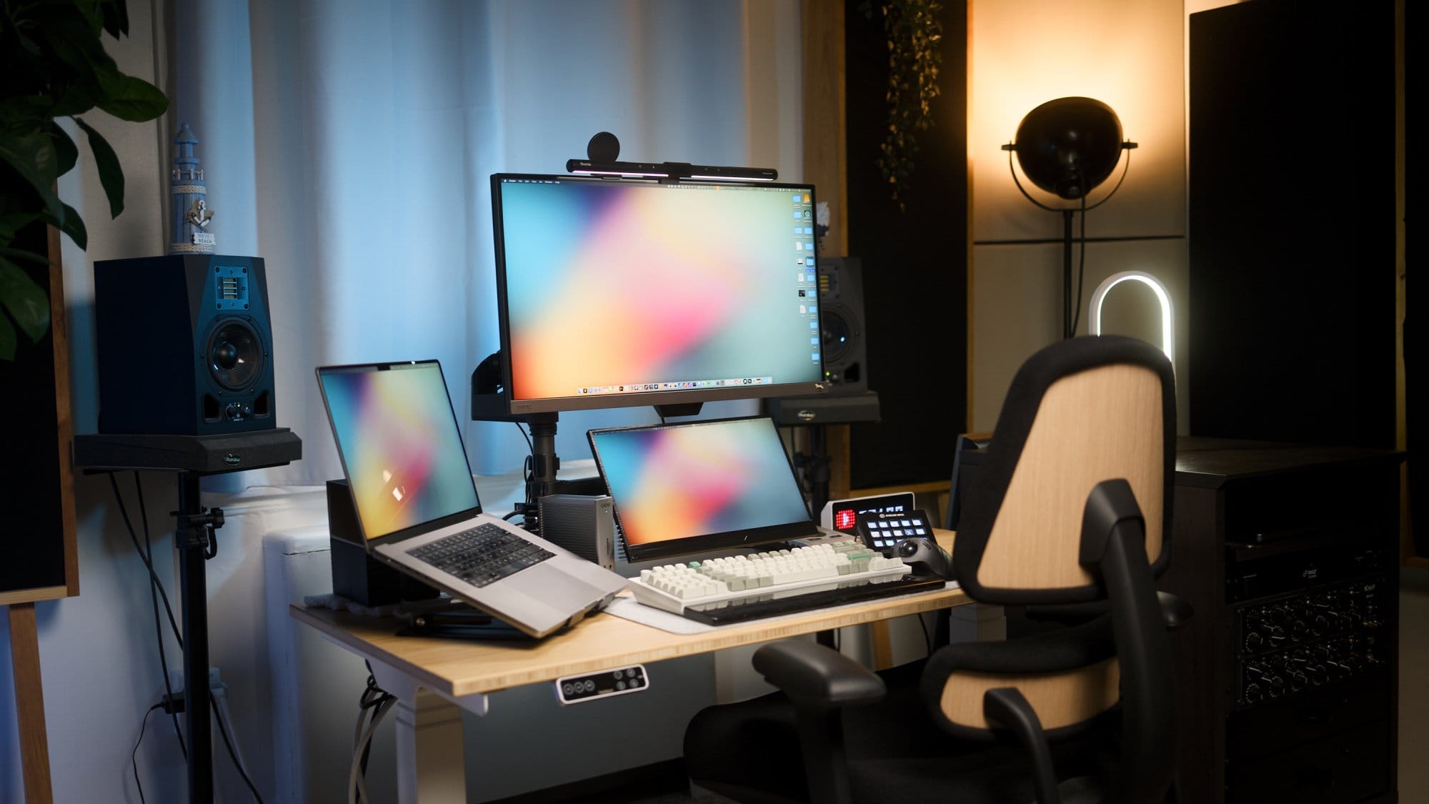 A desk setup with an Anthros Chair, a BenQ EW2780U monitor equipped with a Quintis ScreenLinear Light Bar, an M1 Max MacBook Pro on a Besign LS10 stand, a Keychron Q12 Max keyboard, and a Stream Deck Classic