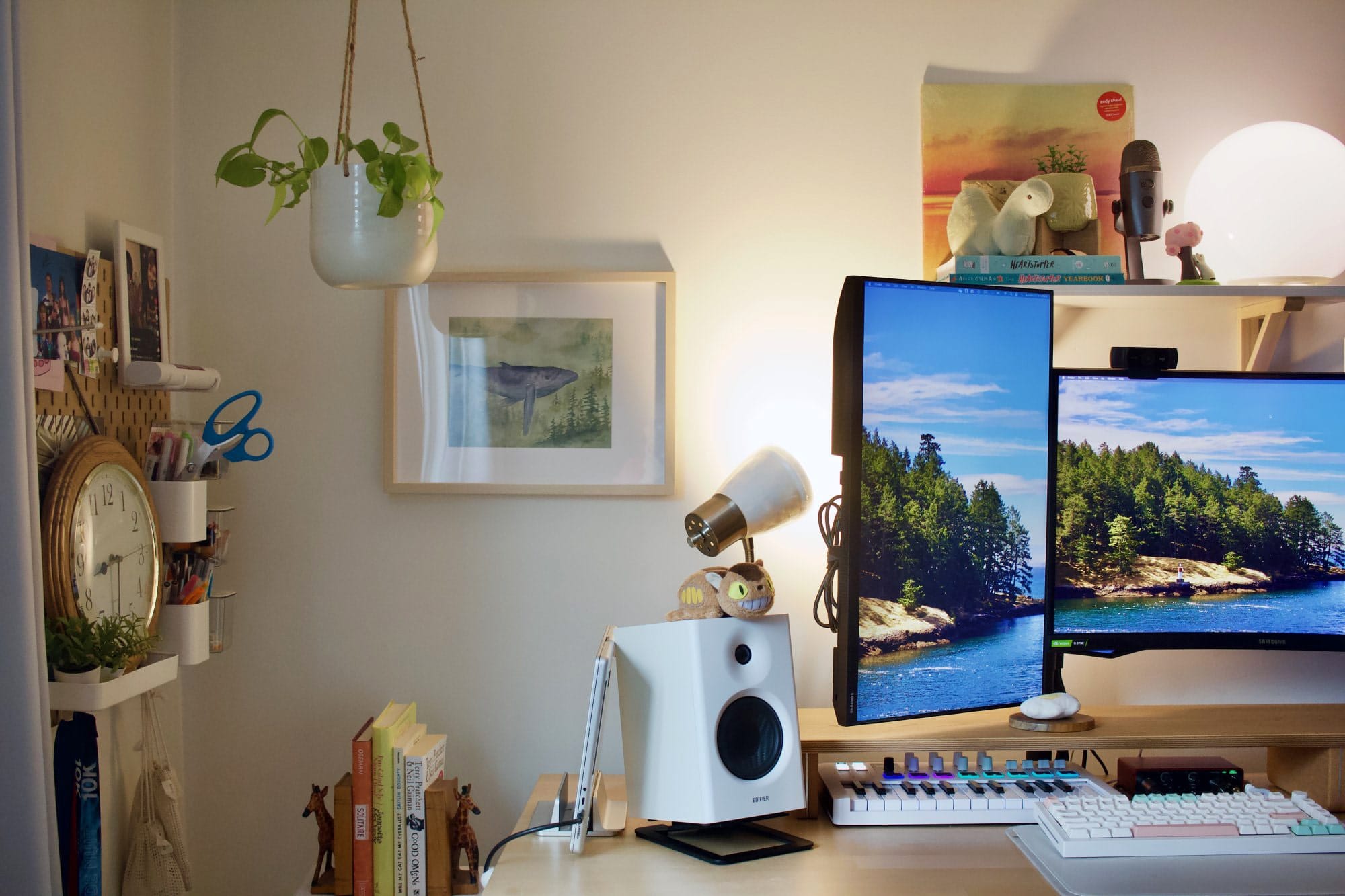 A workspace setup with a Samsung 24″ FHD vertical monitor, an Edifier MR4 speaker, a GMMK Pro keyboard, and a pegboard with a clock, books, and stationery