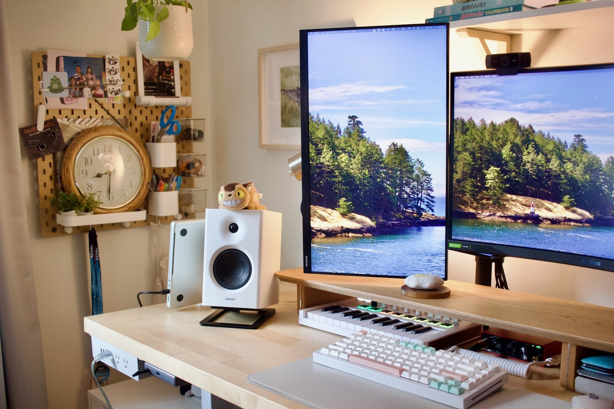 A workspace setup with a Samsung 24″ FHD vertical monitor, an Edifier MR4 speaker, a GMMK Pro keyboard, an Arturia MiniLab 3 MIDI keyboard, and a pegboard with a clock and stationery