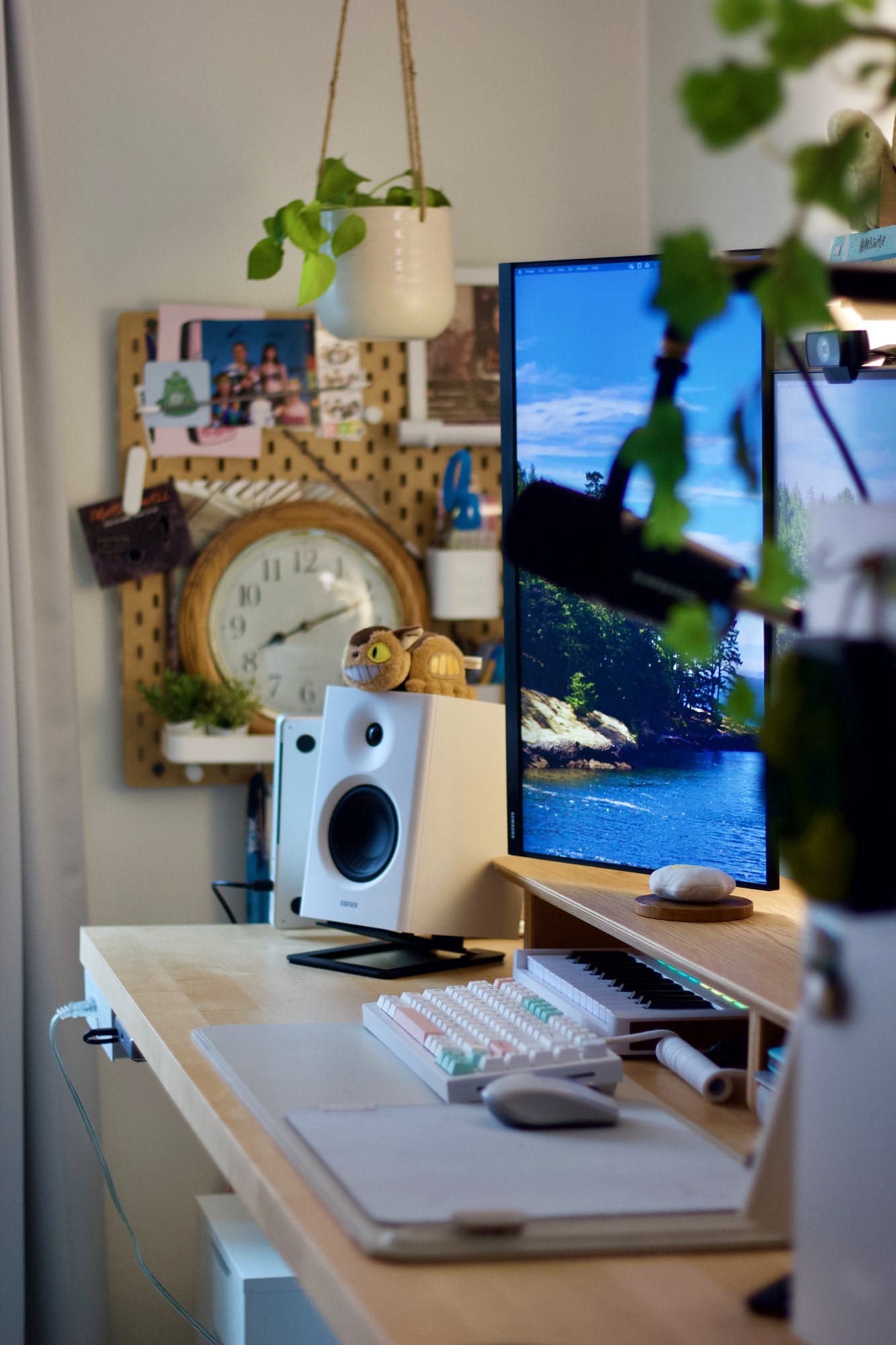 A home desk setup with a Samsung 24″ FHD vertical monitor, a Shure MV7 microphone, an Edifier MR4 speaker, a GMMK Pro keyboard, an Orbitkey desk mat, and a pegboard with a clock and stationery