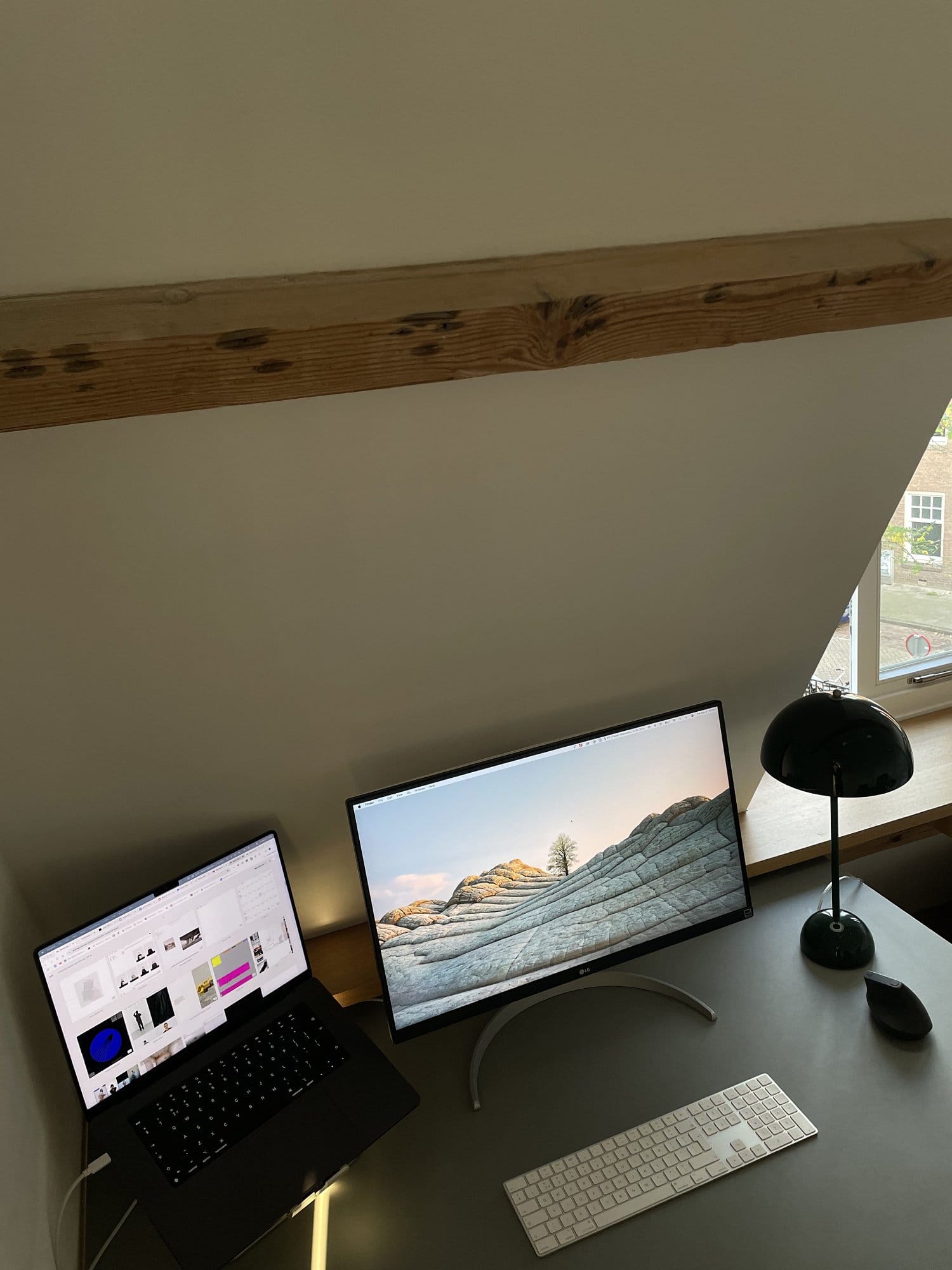 An above view of a home office setup with an LG UltraFine 27UN850-W monitor and a MacBook Pro 14″