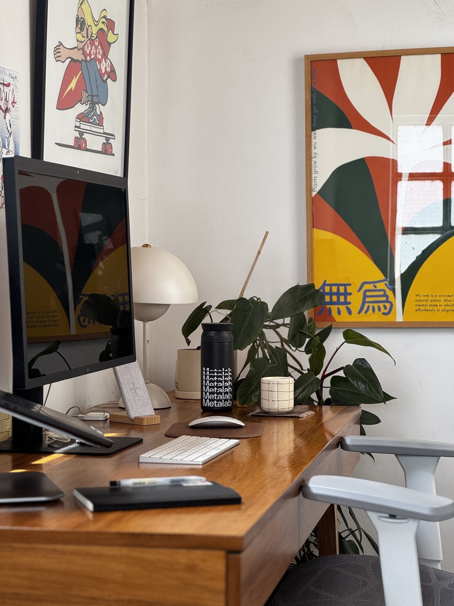 A workspace setup with an LG UltraFine 4K monitor, an Apple Keyboard, an Apple Magic Mouse, and an Actek Floe Plus EC727 chair, with a laptop on a Rain Design mStand360 and a notebook with a pen on the wooden desk