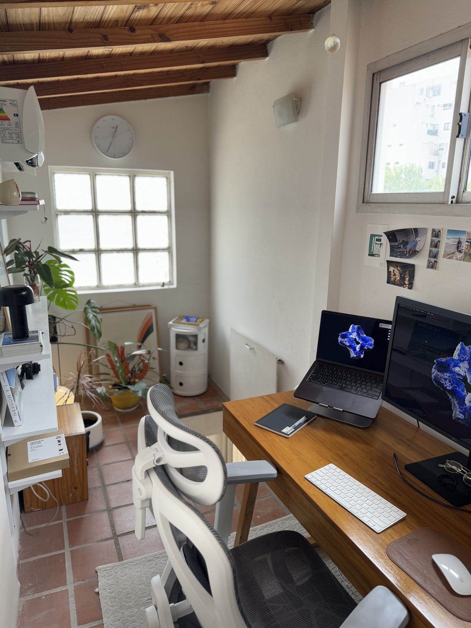 A home workspace featuring an Apple MacBook Pro M3 Pro, an external monitor, an Apple Keyboard, an Apple Magic Mouse, and an ergonomic chair